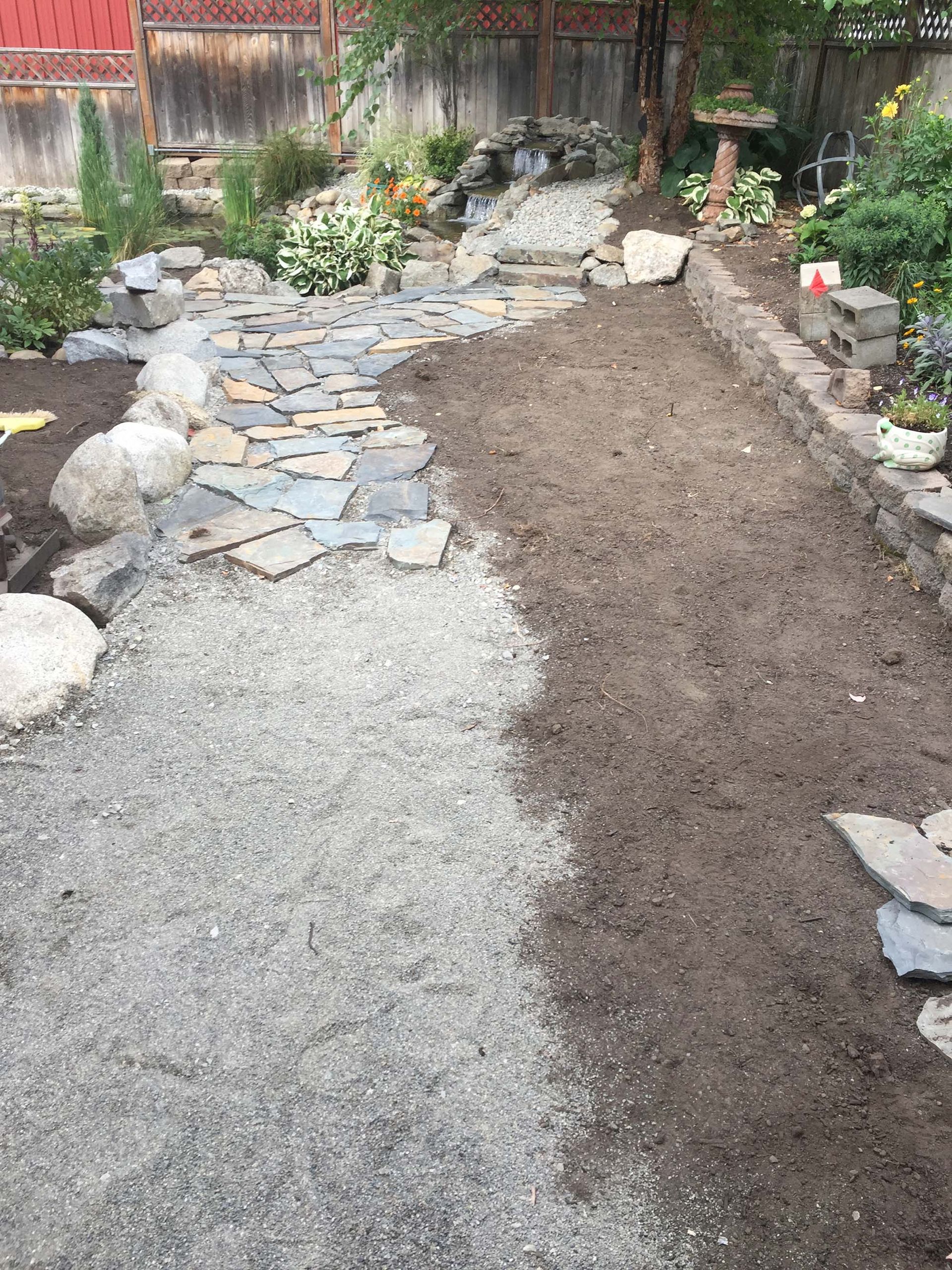 A stone walkway is being built in a backyard.