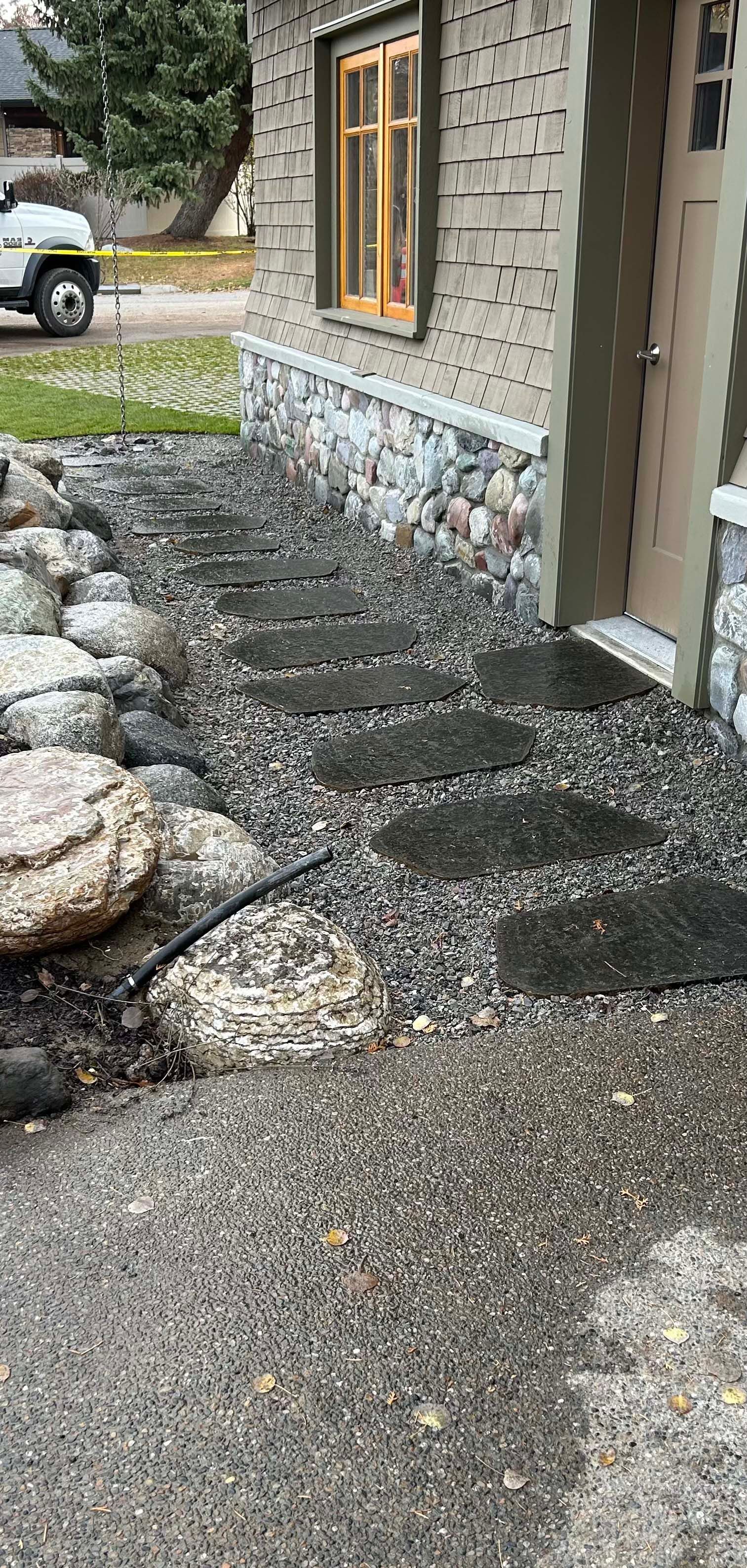 A white truck is parked in front of a house with a stone wall.