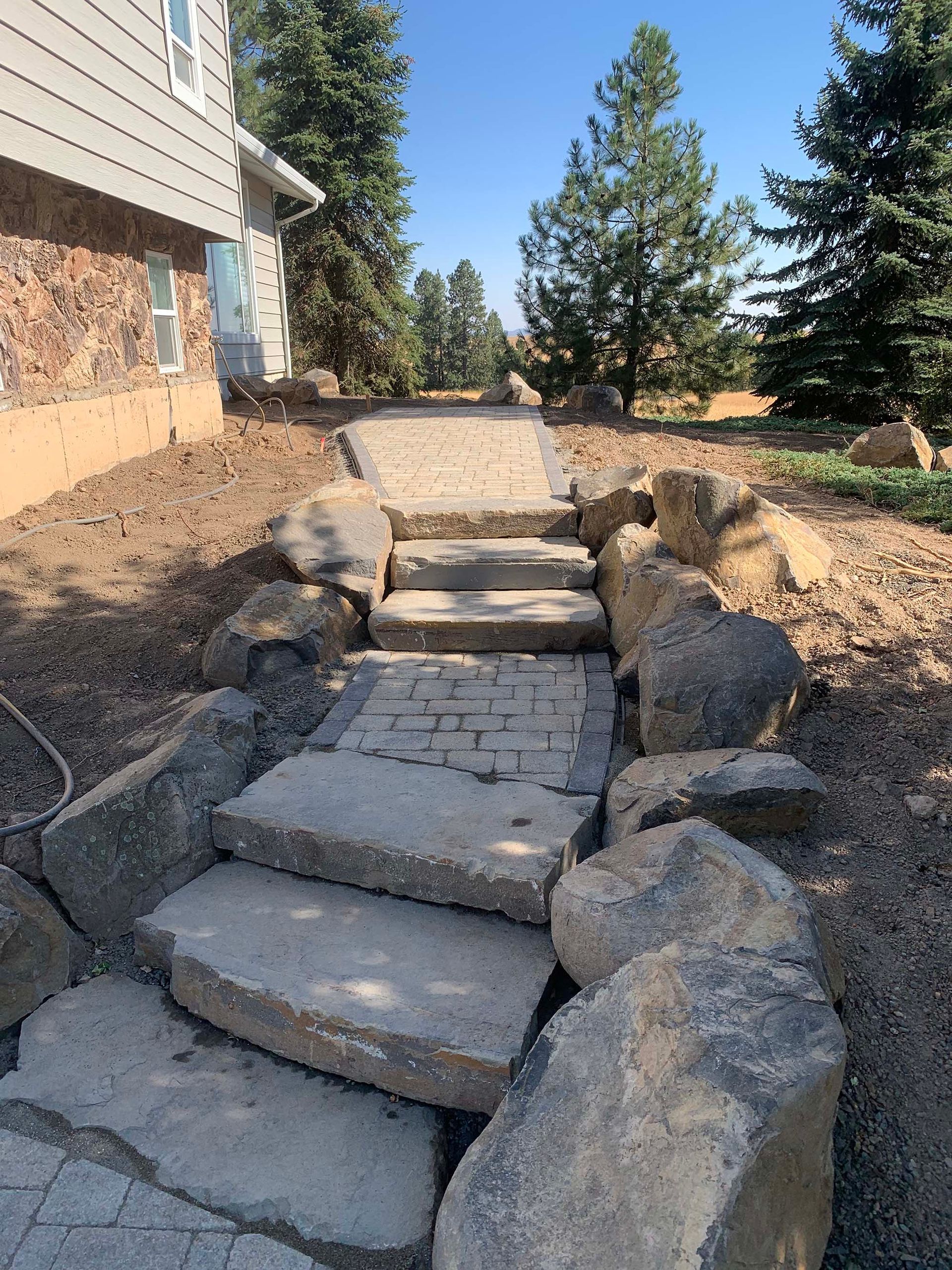 A stone walkway leading to a house surrounded by rocks.
