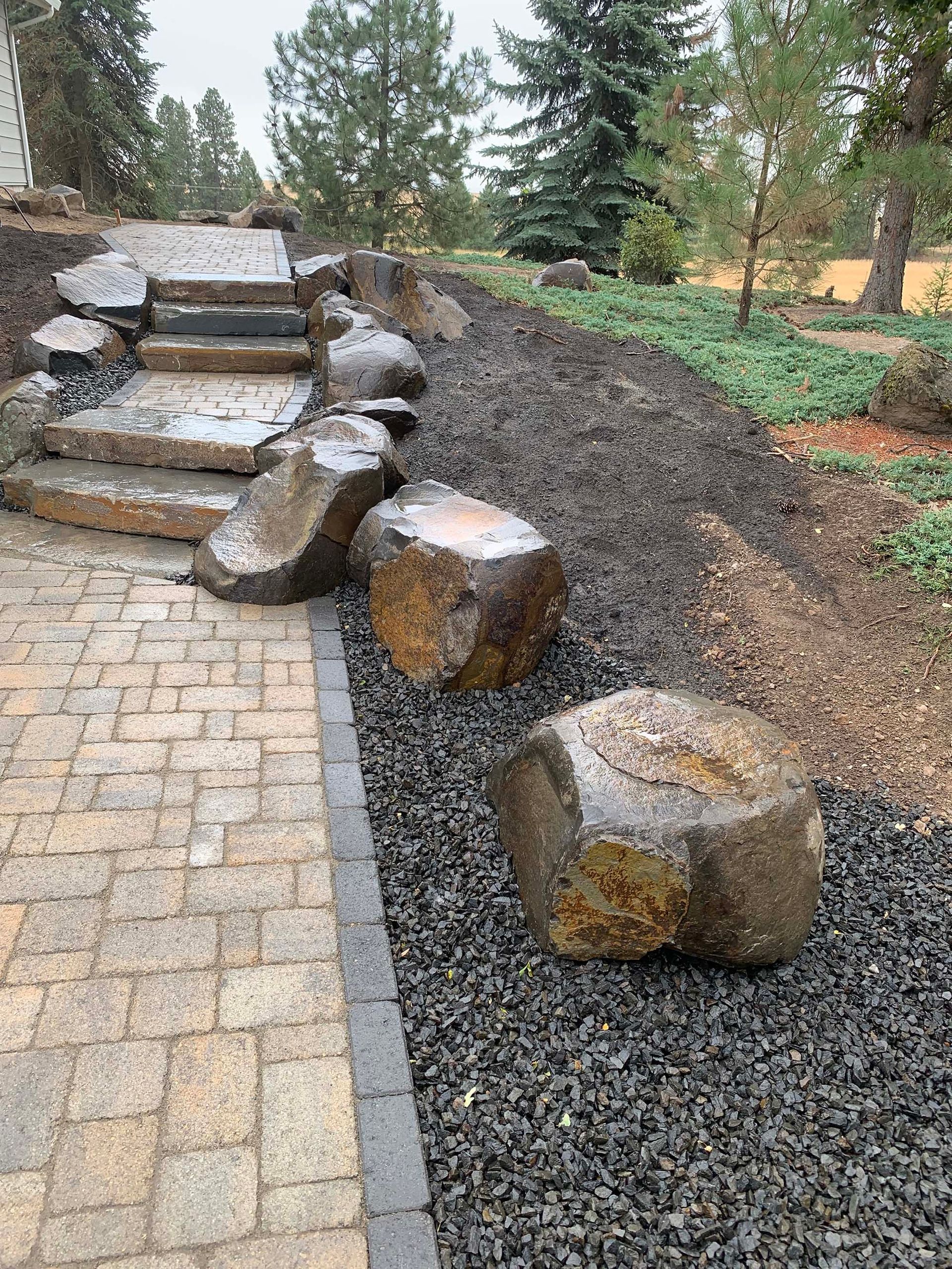 A brick walkway with stairs and rocks on the side of it.