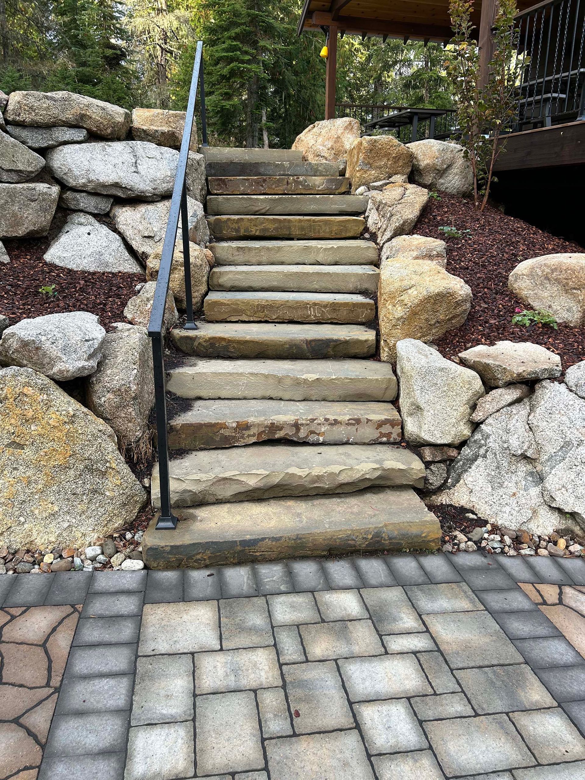 A set of stairs leading up to a stone wall surrounded by rocks.