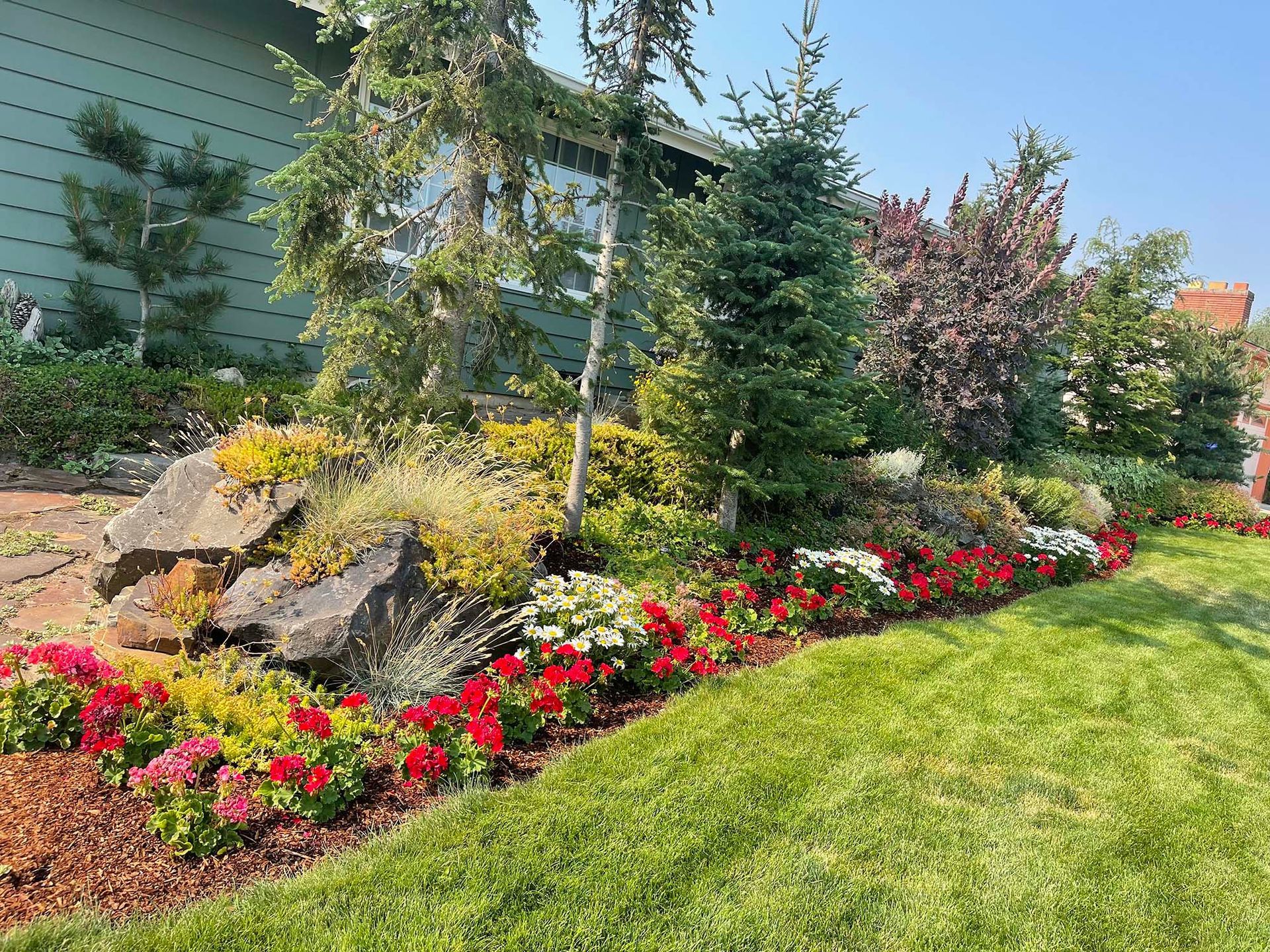 A garden with flowers and rocks in front of a house.