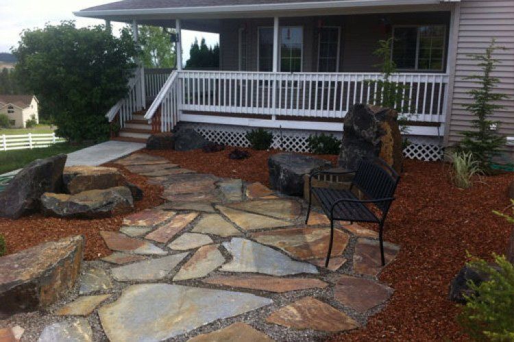 A stone walkway leading to a porch of a house.