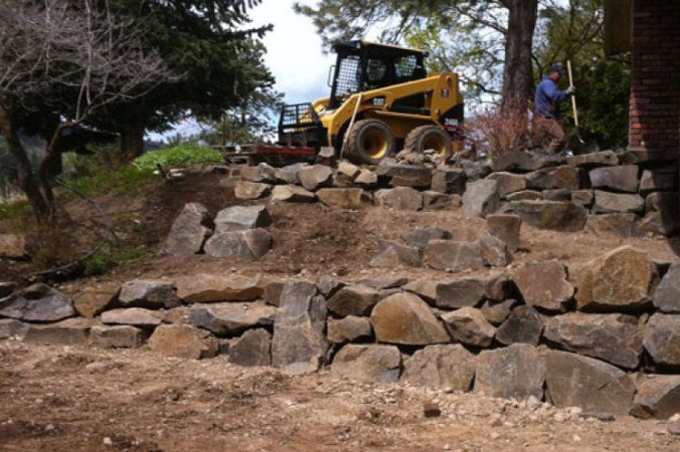 A yellow bulldozer is sitting on top of a pile of rocks.