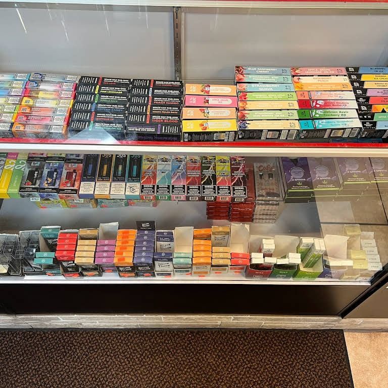A display case at a store showcasing various disposable vapes in colorful packaging.