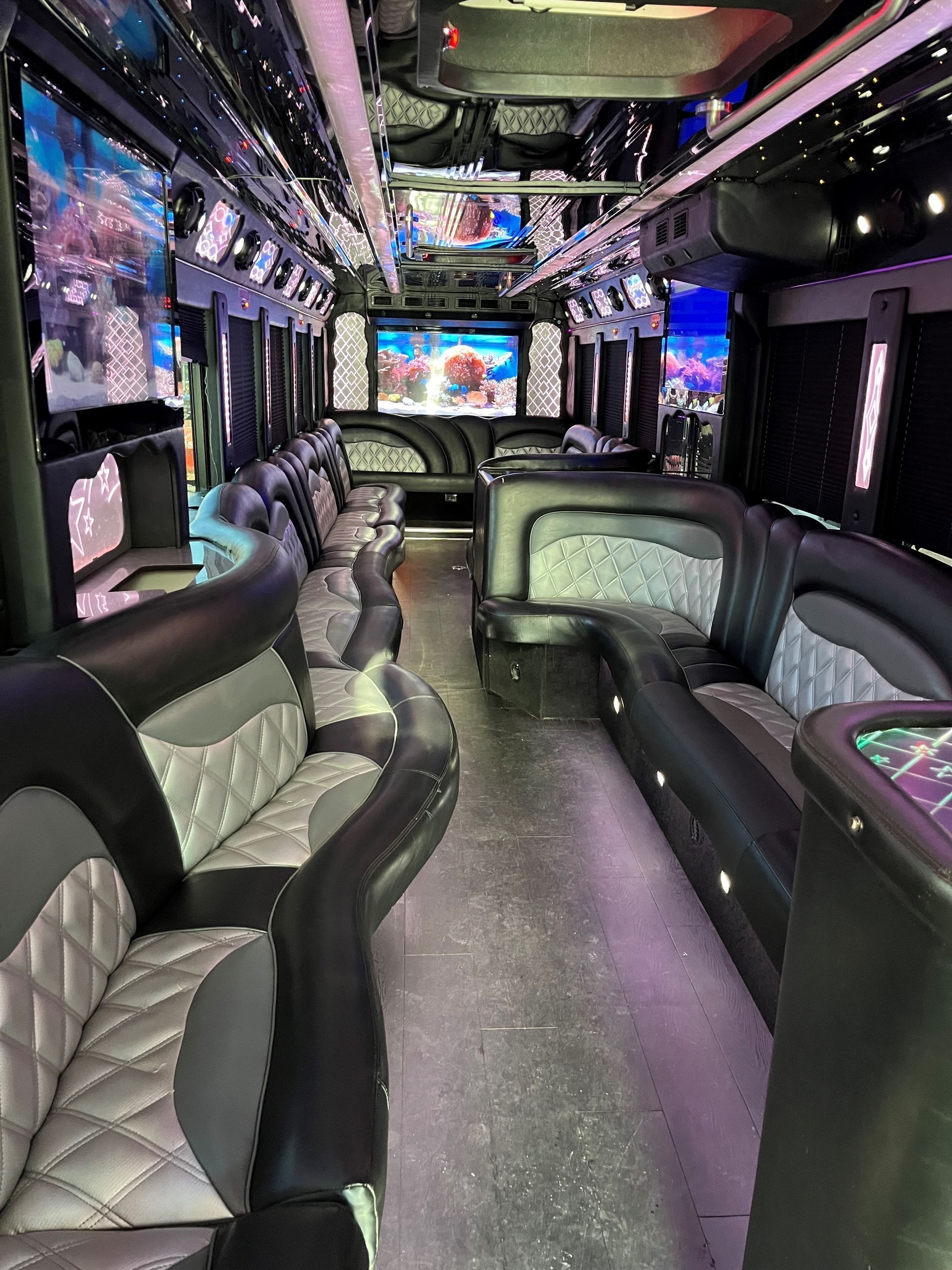 The inside of a limousine with a lot of seats and televisions.