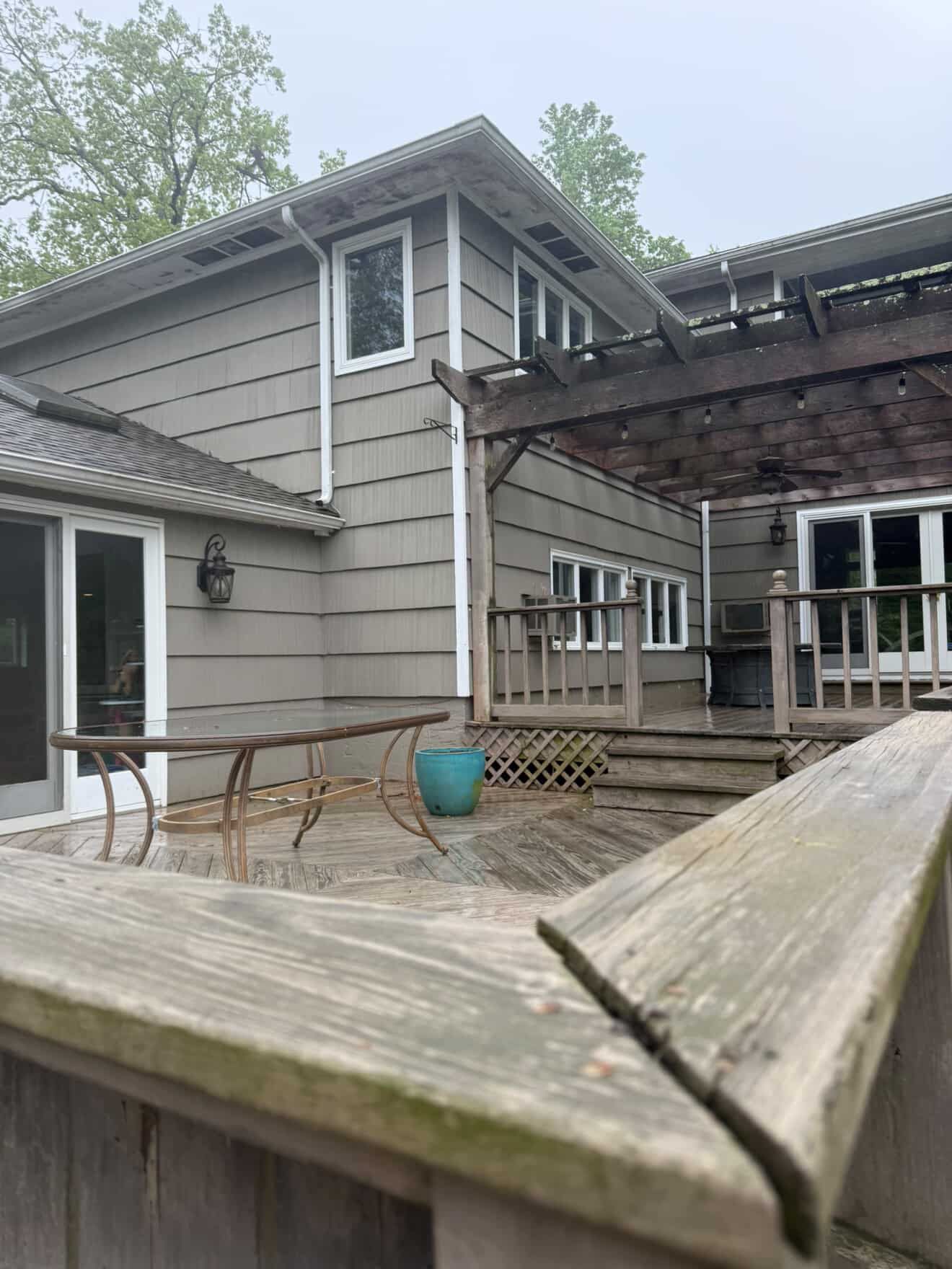 The back of a house with a wooden deck and a pergola.