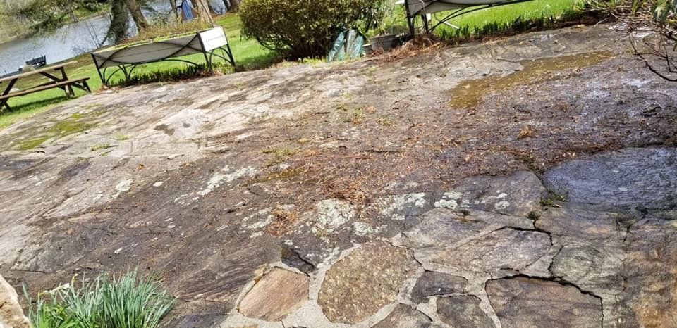 A stone patio with a picnic table and chairs in the background.