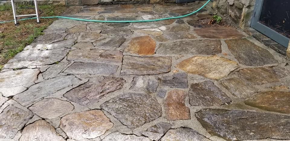 A stone patio with a green hose attached to it.