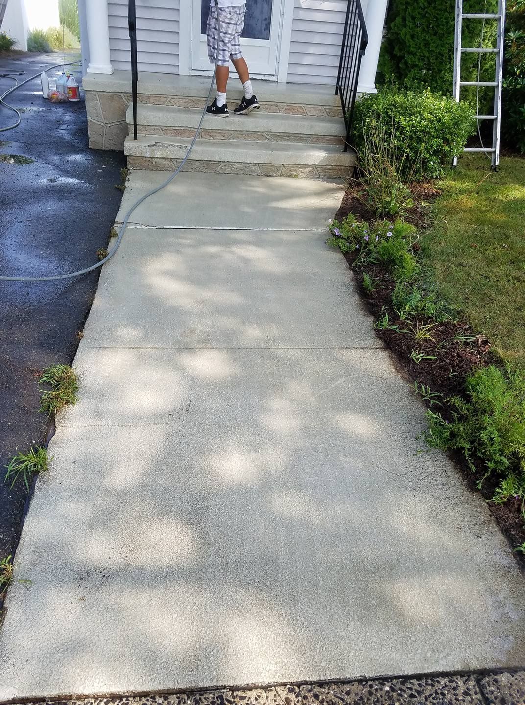 A man is standing on a sidewalk in front of a house.