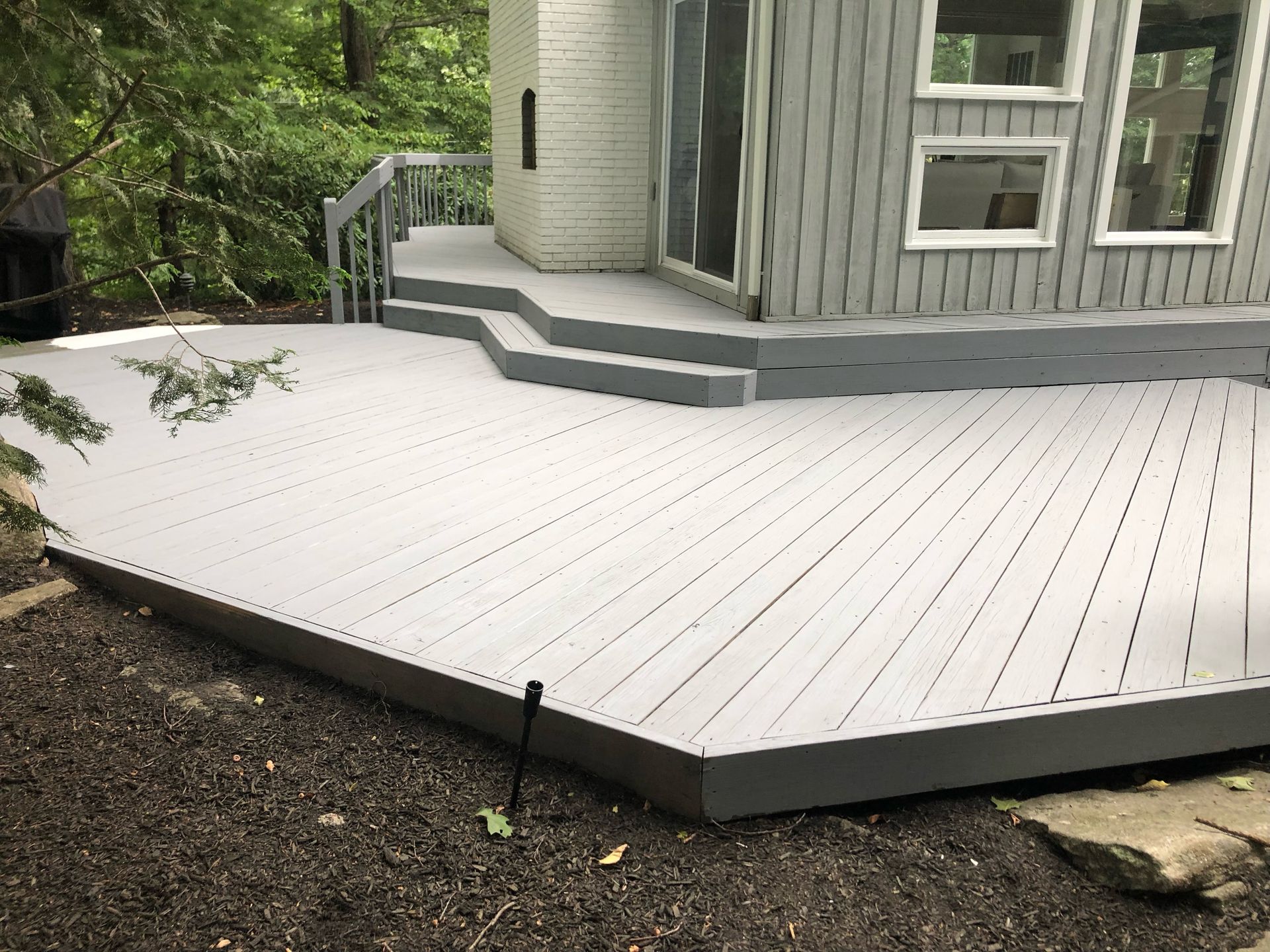 A gray deck is sitting in front of a house.