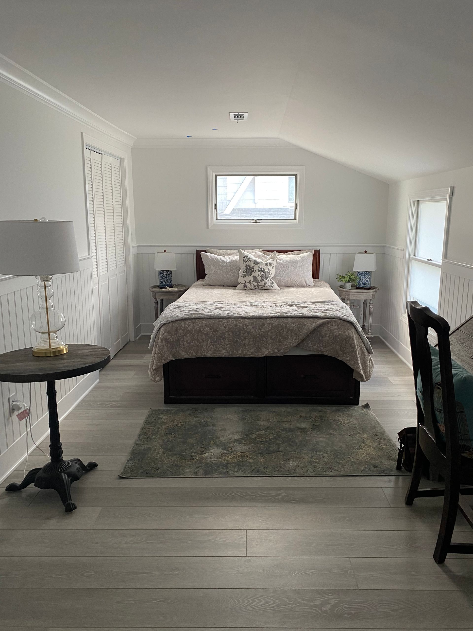 A bedroom with a bed, table, chairs, and a window.