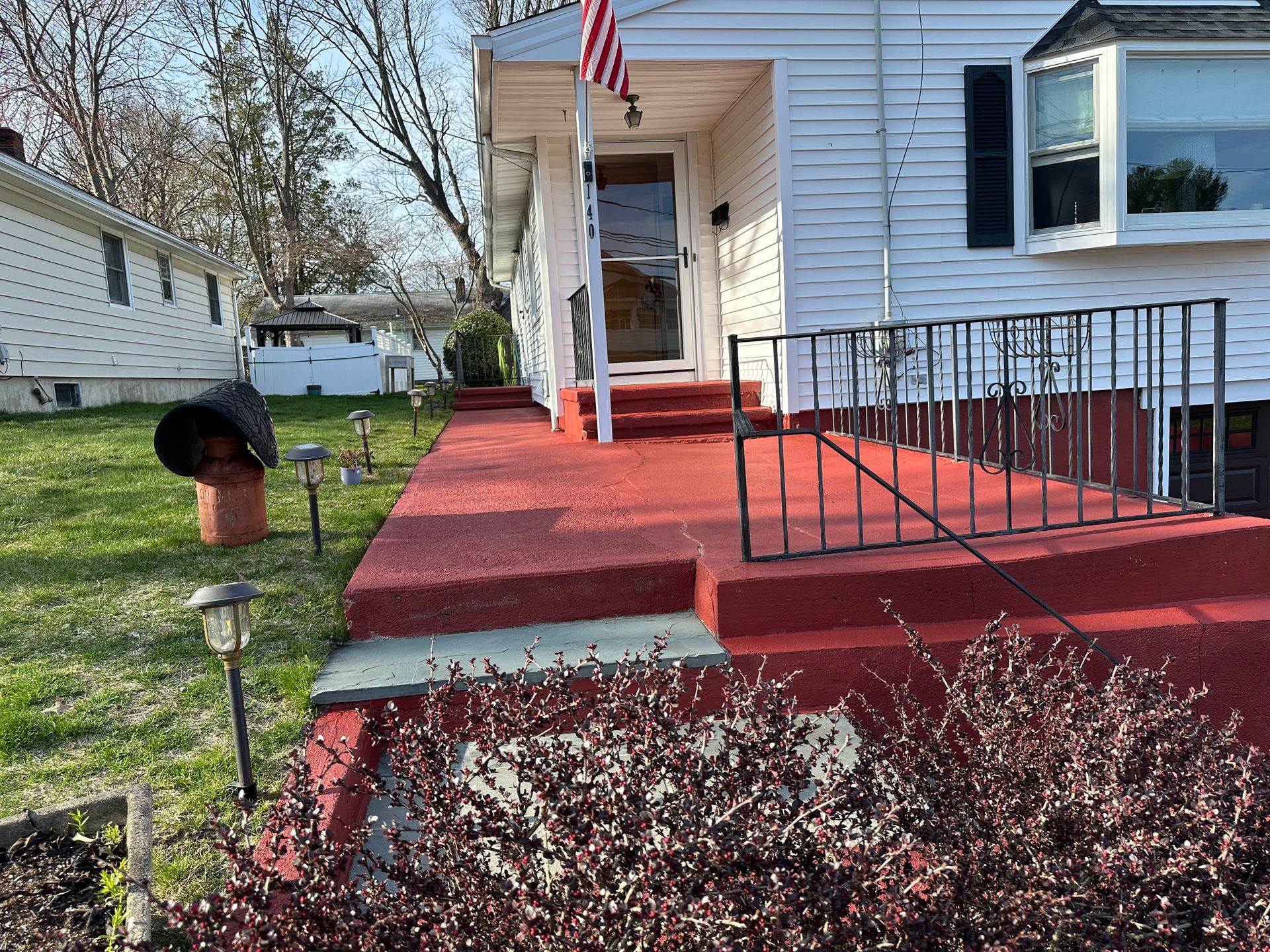 A white house with a red porch and stairs.