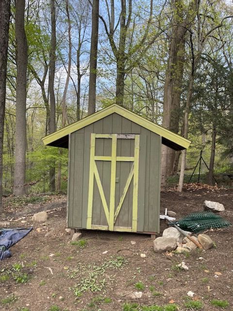 A green and yellow shed in the middle of a forest.