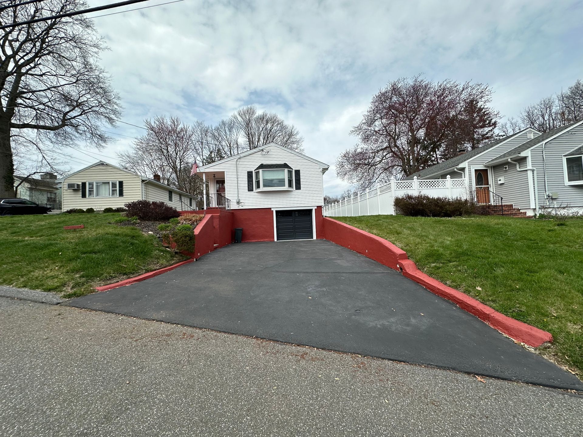 A white house with a red driveway leading to it.
