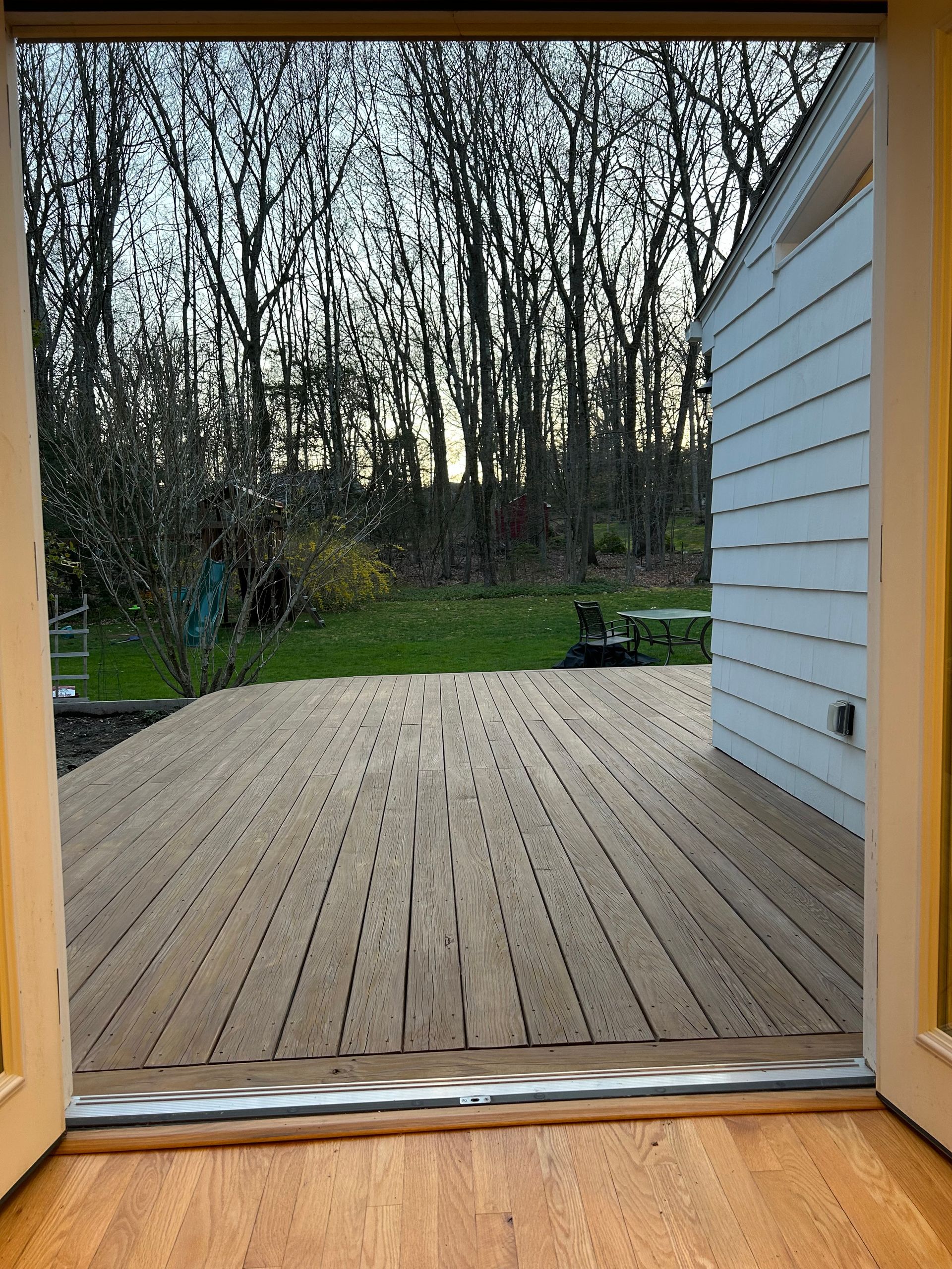 A view of a wooden deck through a sliding glass door.