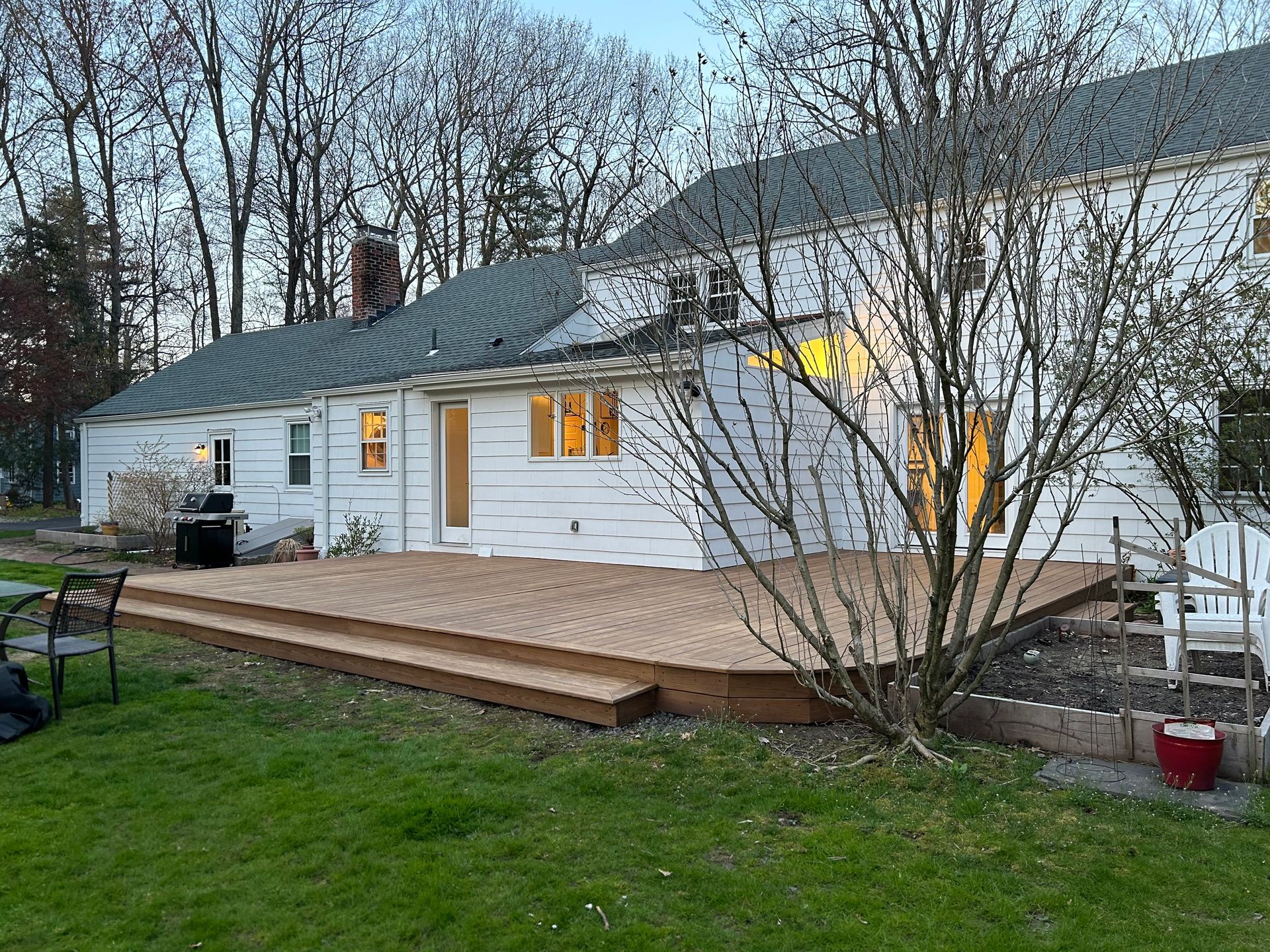 A white house with a wooden deck in front of it.
