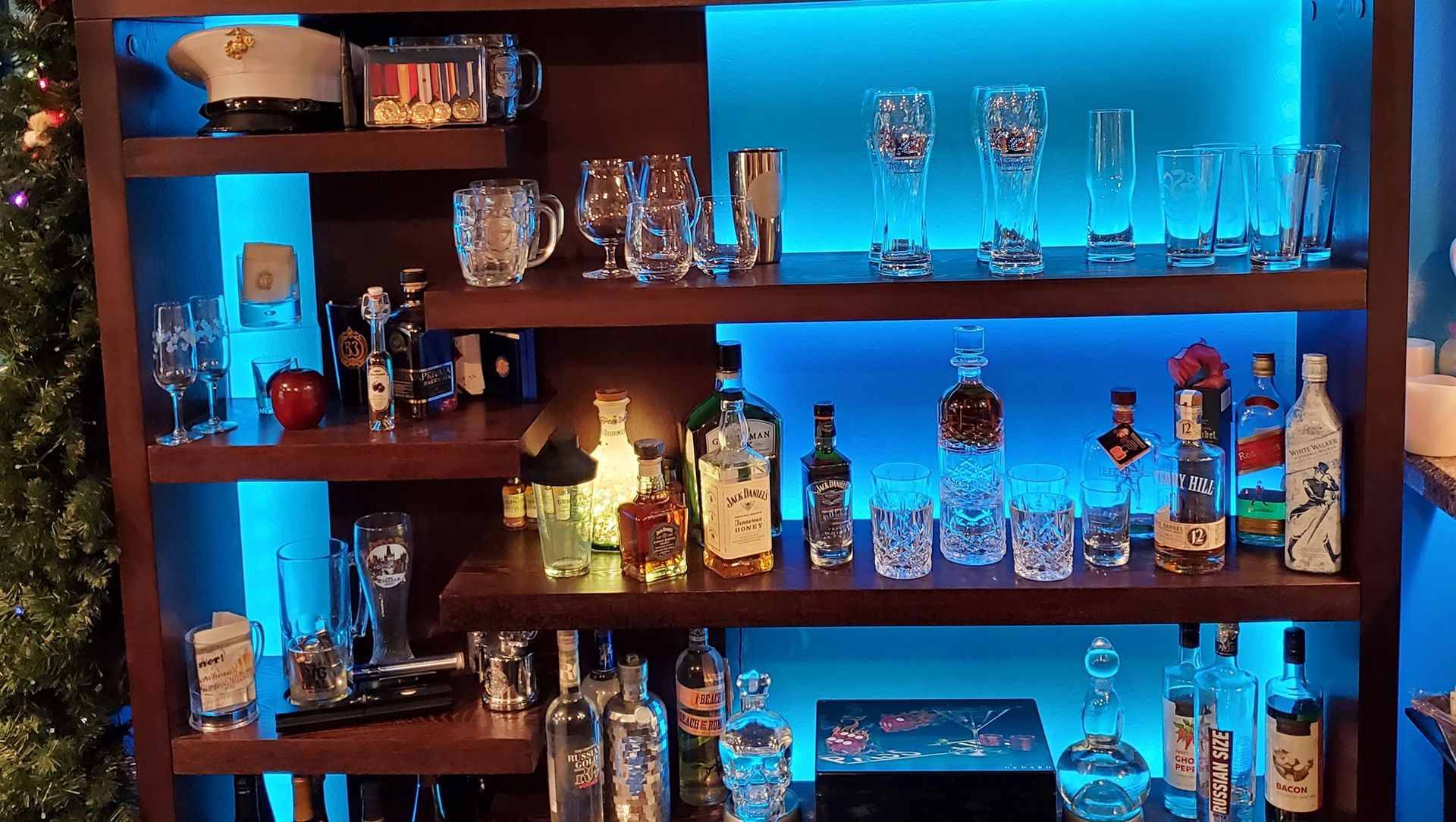 Wooden bar shelves with liquor bottles, glassware, and blue LED lighting.