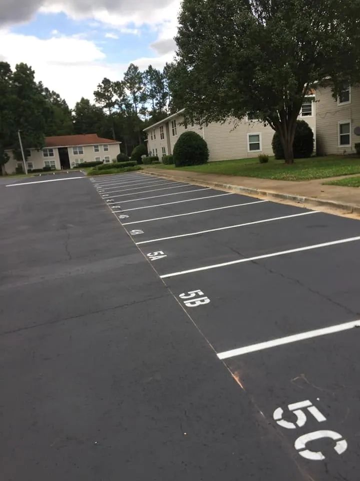 A row of numbered parking spaces, labeled 5A through 5C and beyond, in front of an apartment building.