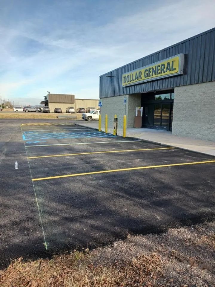 A Dollar General storefront with a newly paved parking lot featuring painted blue accessible parking spaces.