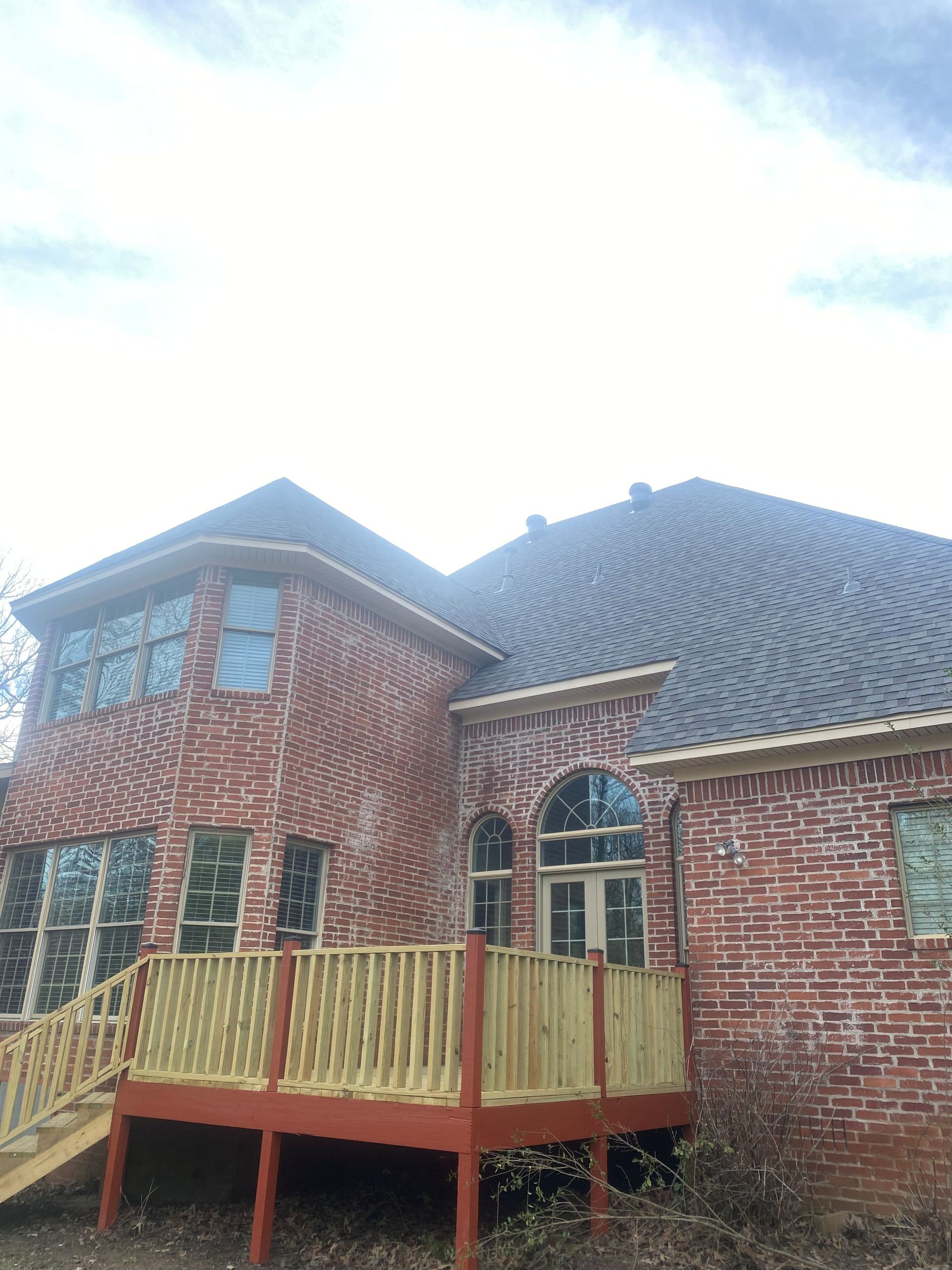 Red brick house with a wooden deck; overcast sky.