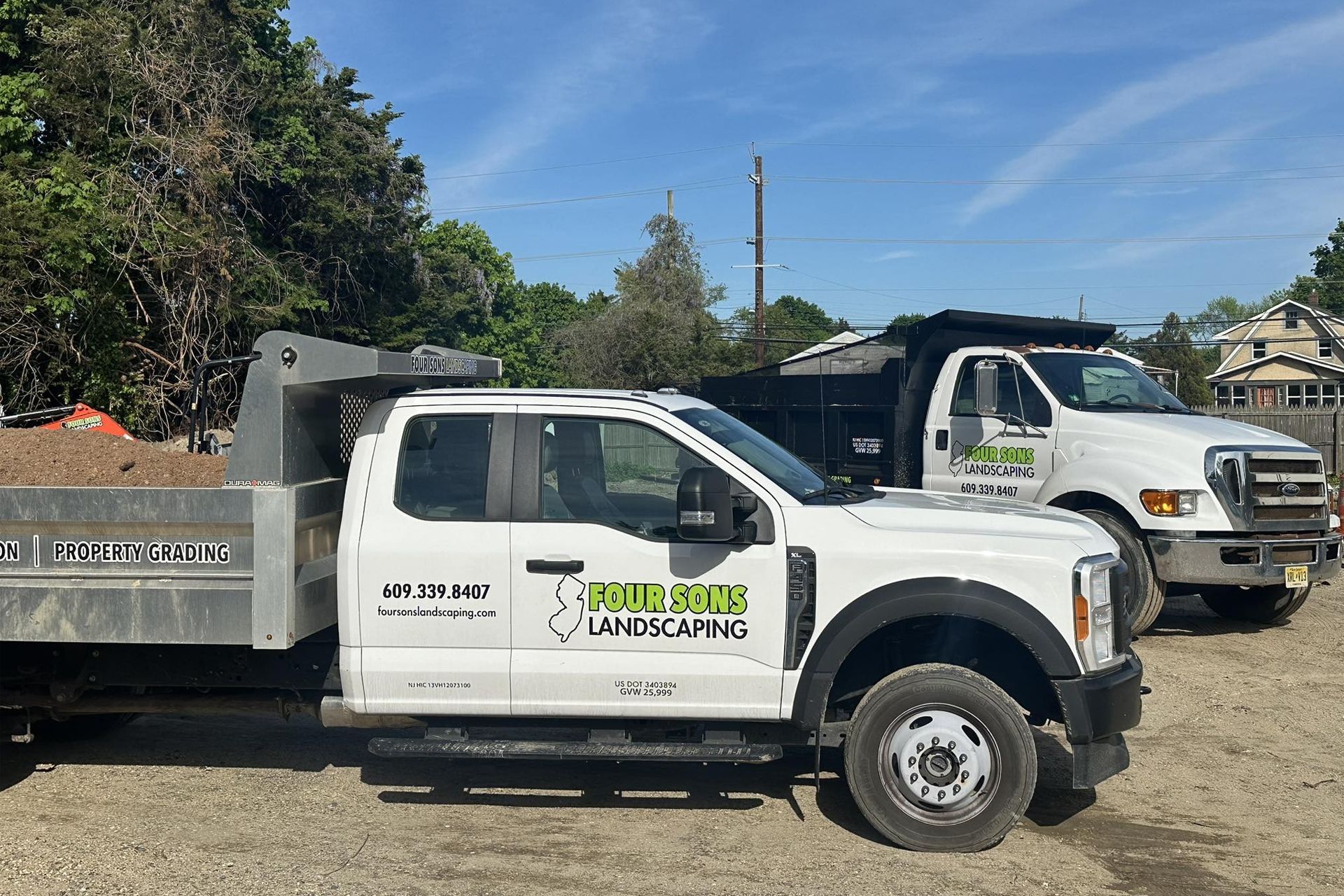 Two white Ford dump trucks with the name
