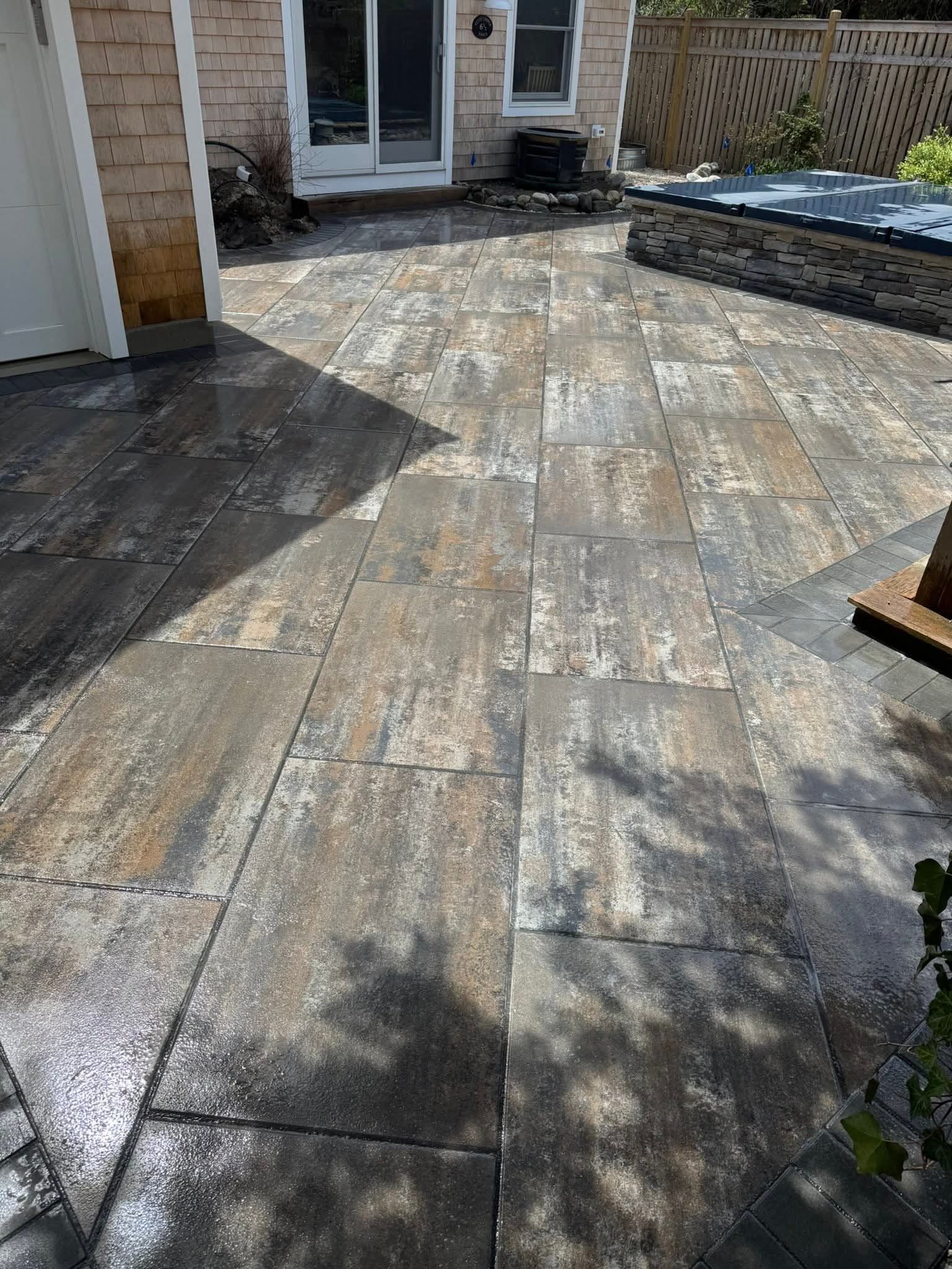 Stone patio with varied colors and textures; next to a building with glass doors.