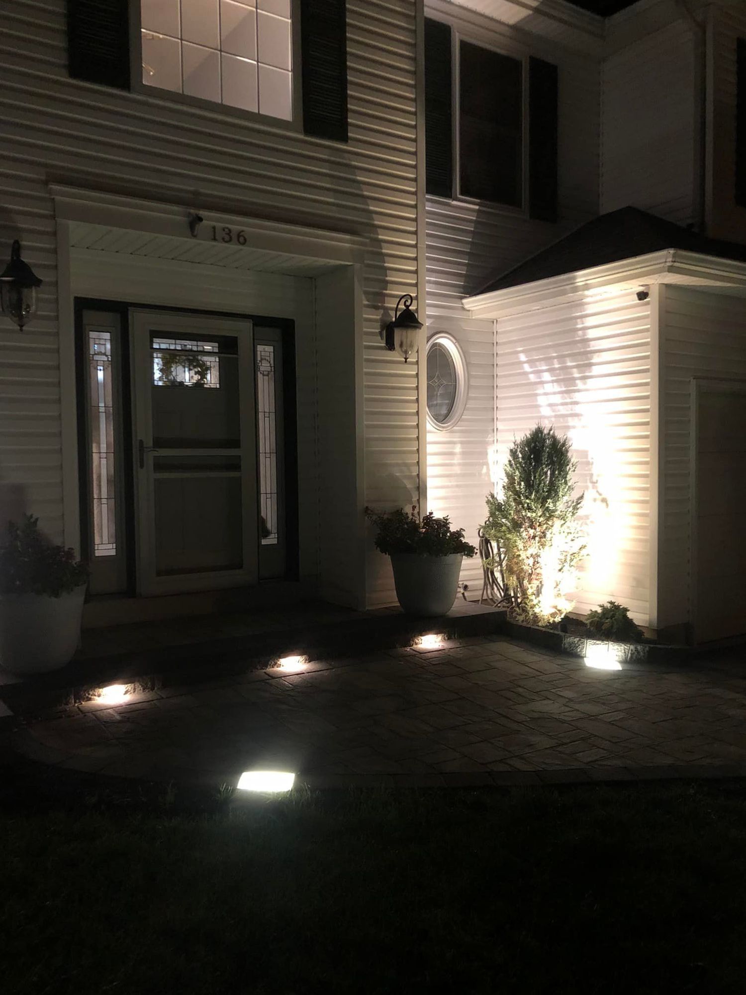 Night view of a house with exterior lighting. Square ground lights illuminate a pathway.
