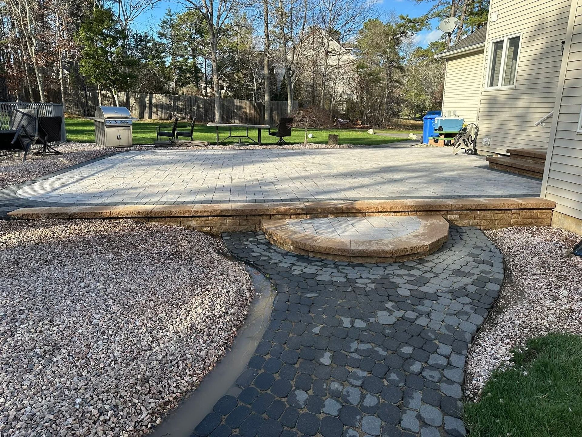Stone patio with a raised fire pit area and a gravel border.