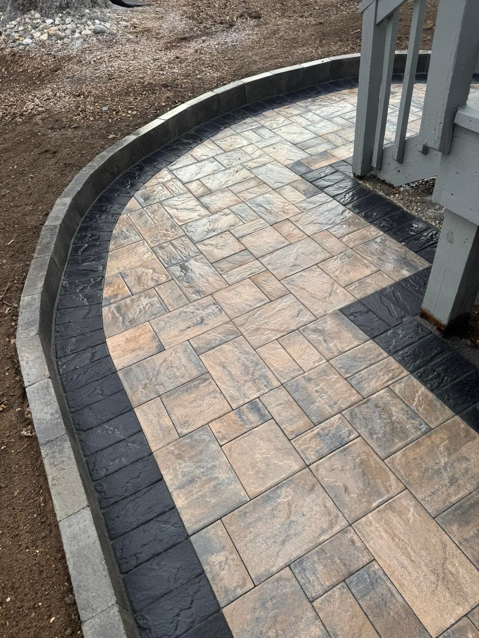 Curved paved patio with border, leading to deck support.