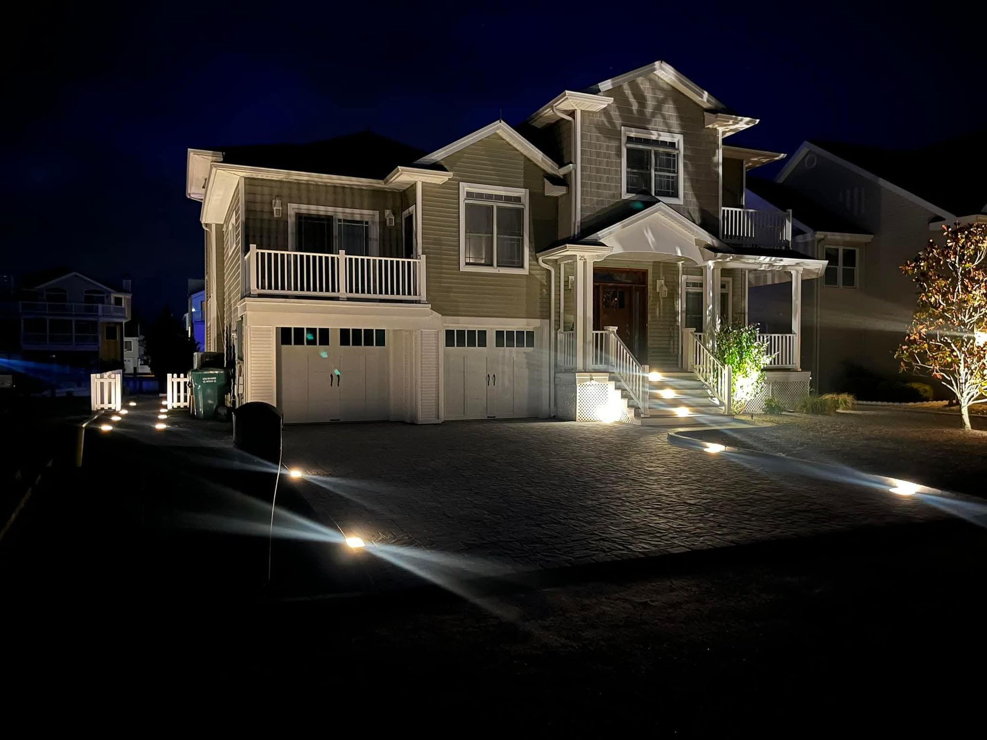 Night view of a two-story house with pathway lights illuminating the front yard and steps.