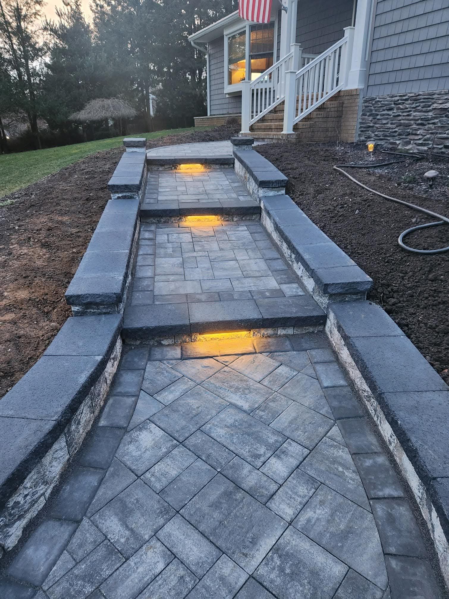 Stone steps leading up to a house, illuminated by lights.