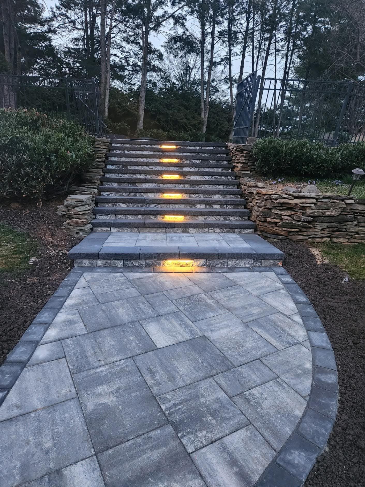 Stone staircase with built-in lights leading up a hill, path in foreground.