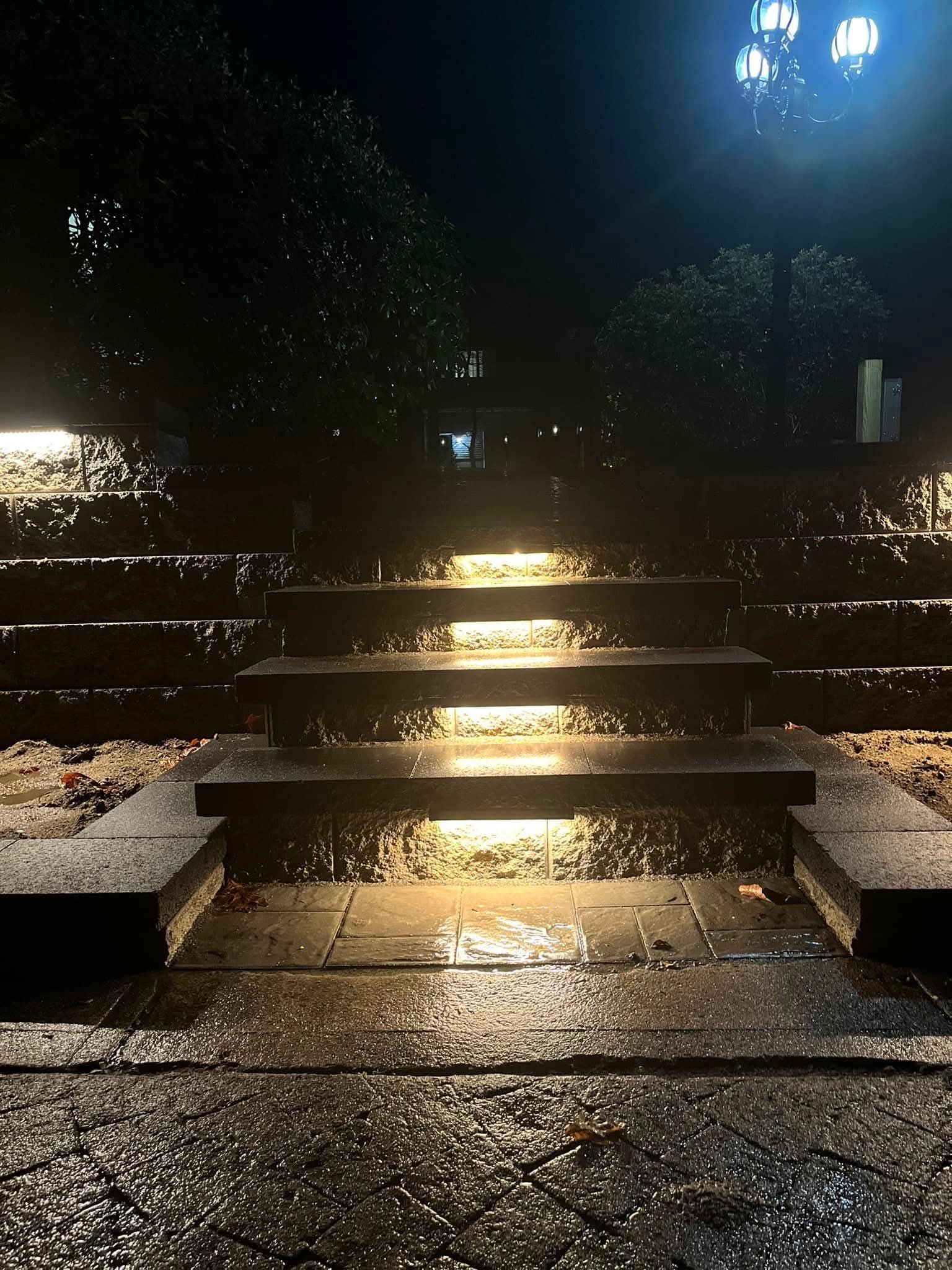 Stone steps illuminated at night, wet from rain.