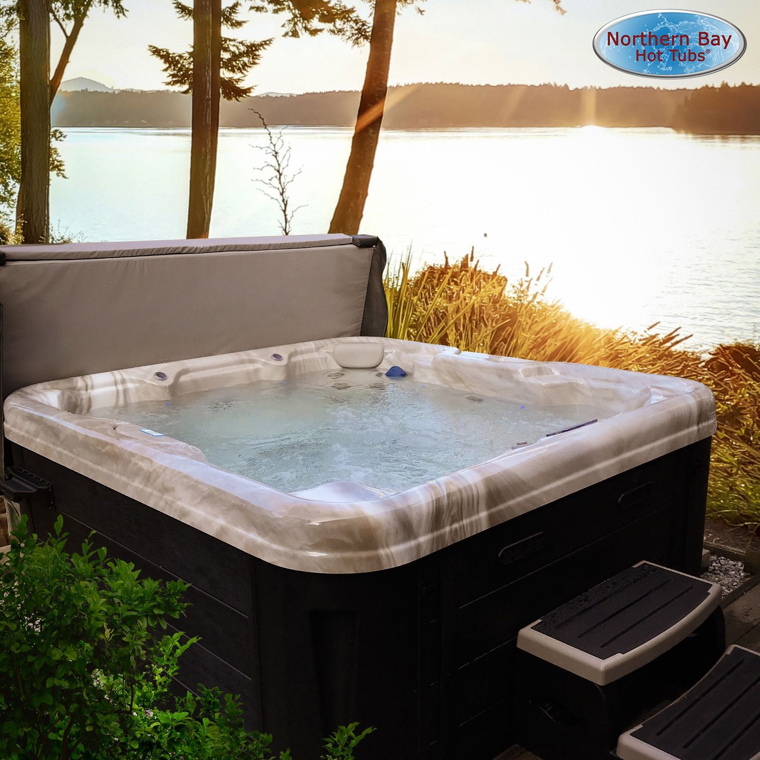Hot tub with open cover, steps, and lake backdrop during a sunny day.