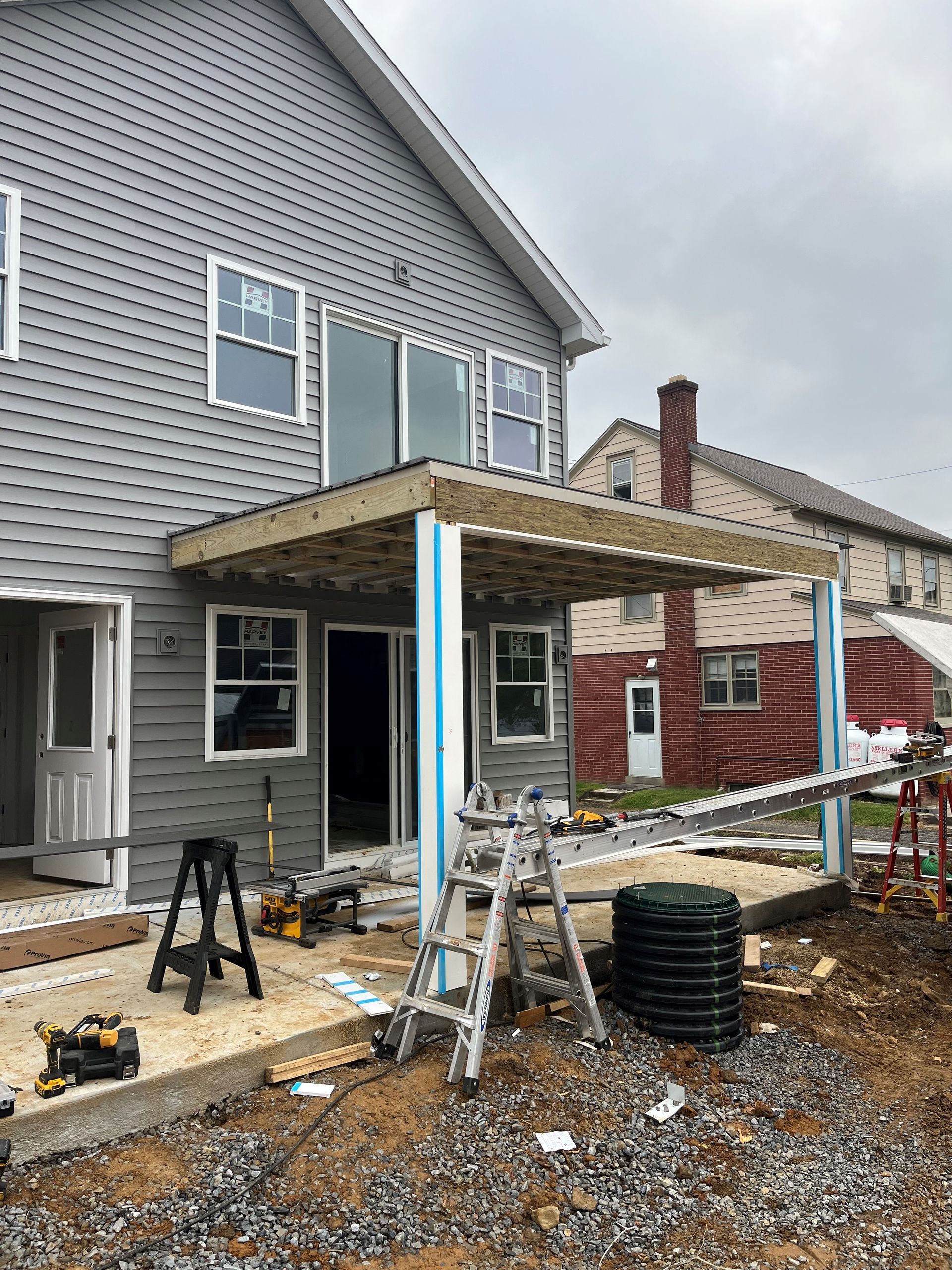 A house is being built with a porch and a ladder in front of it.
