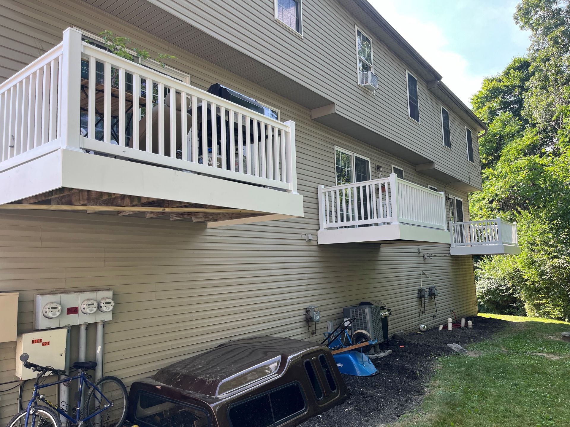 A jeep is parked in front of a house with balconies.