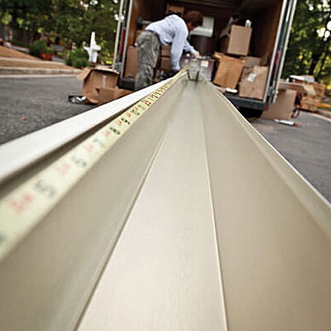 A man is measuring a piece of metal with a tape measure.