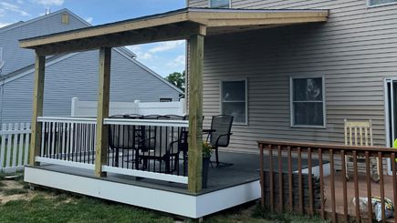 A deck with a table and chairs on it in front of a house.