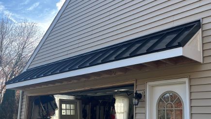 A house with a black awning over the garage door.
