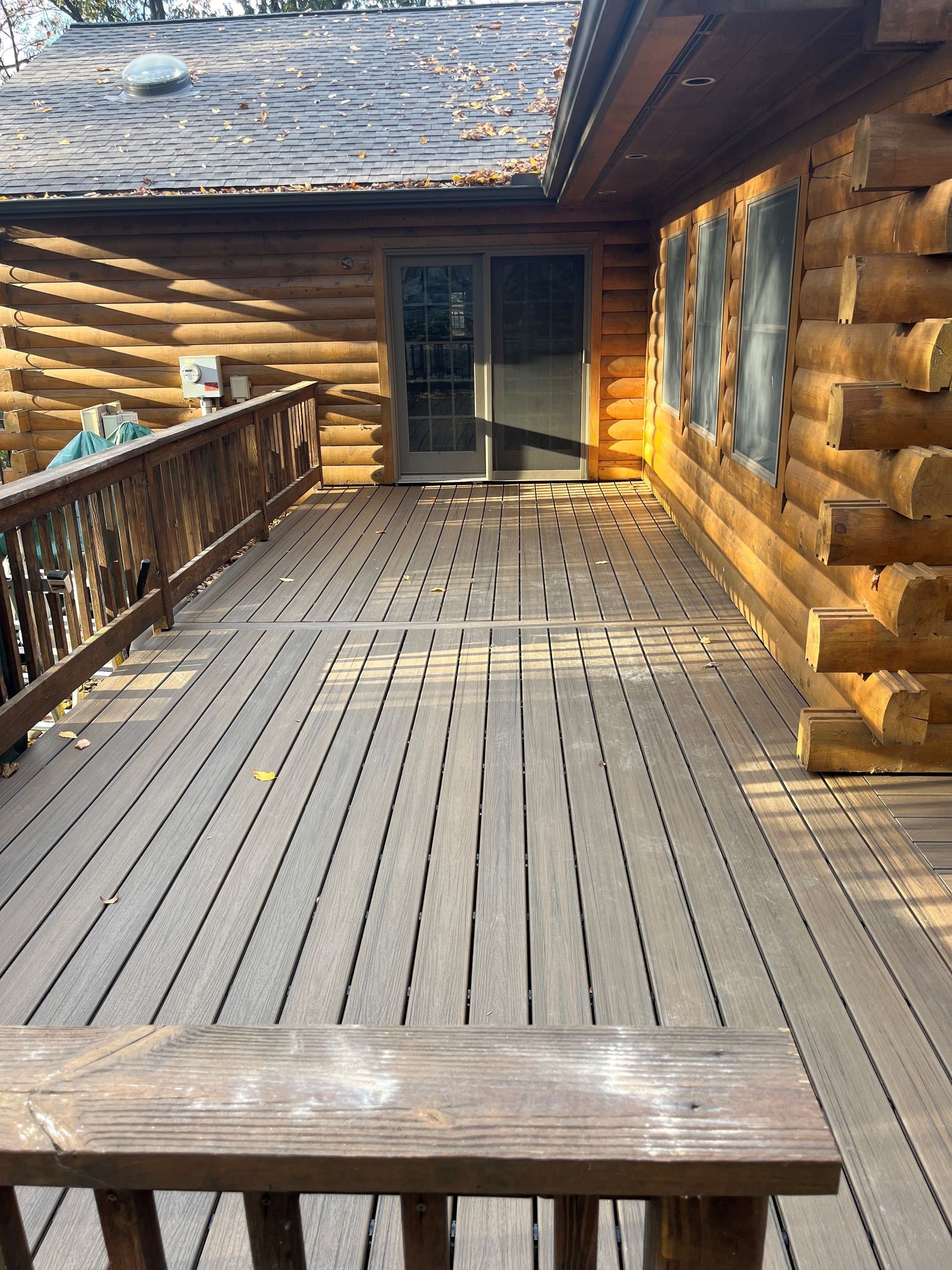 A wooden deck with a bench in front of a log cabin