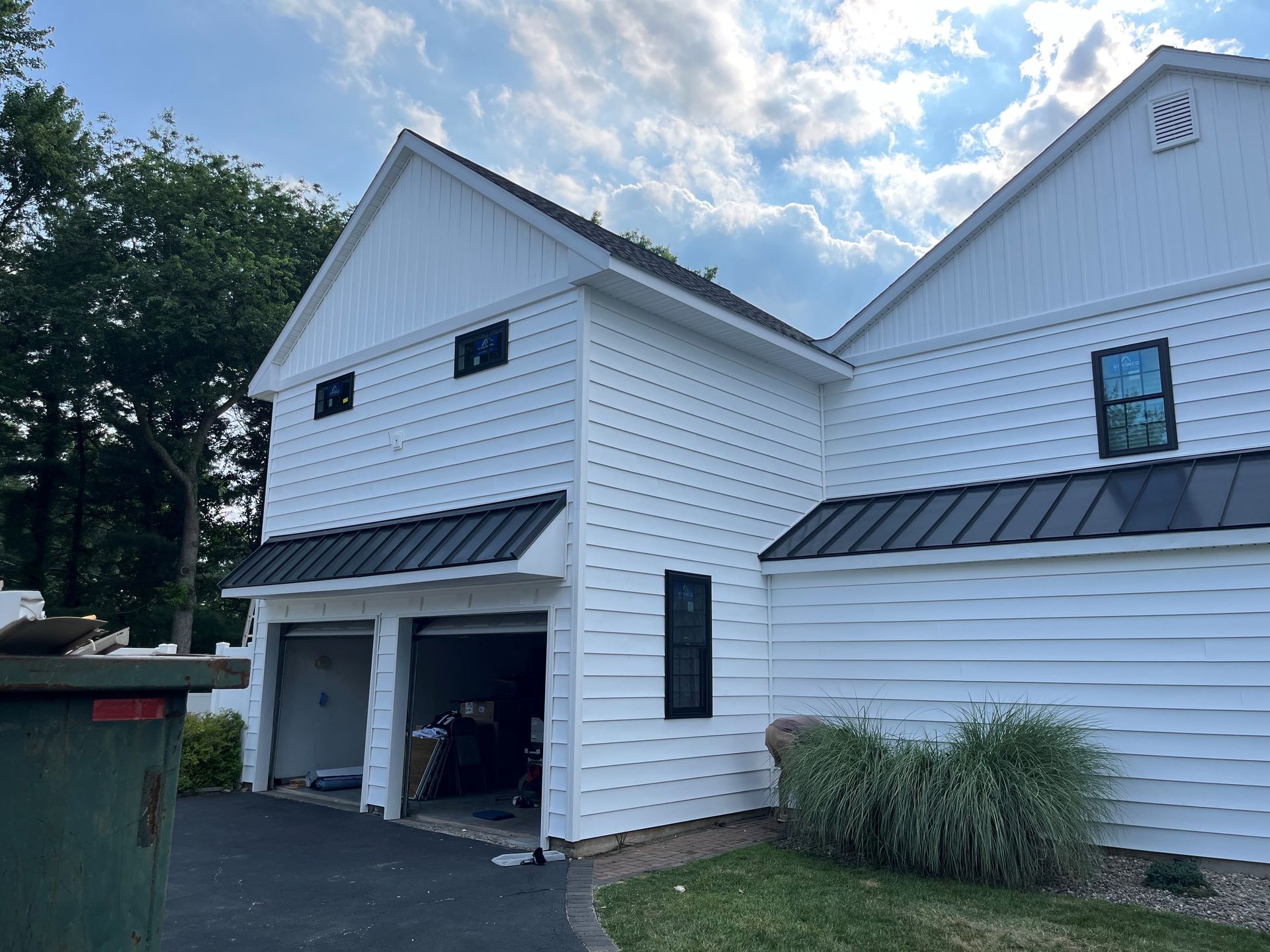 A white house with a garage and a black roof.