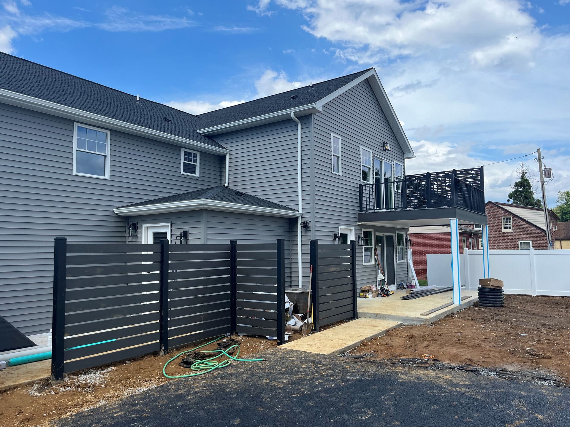 A large gray house with a black fence in front of it.
