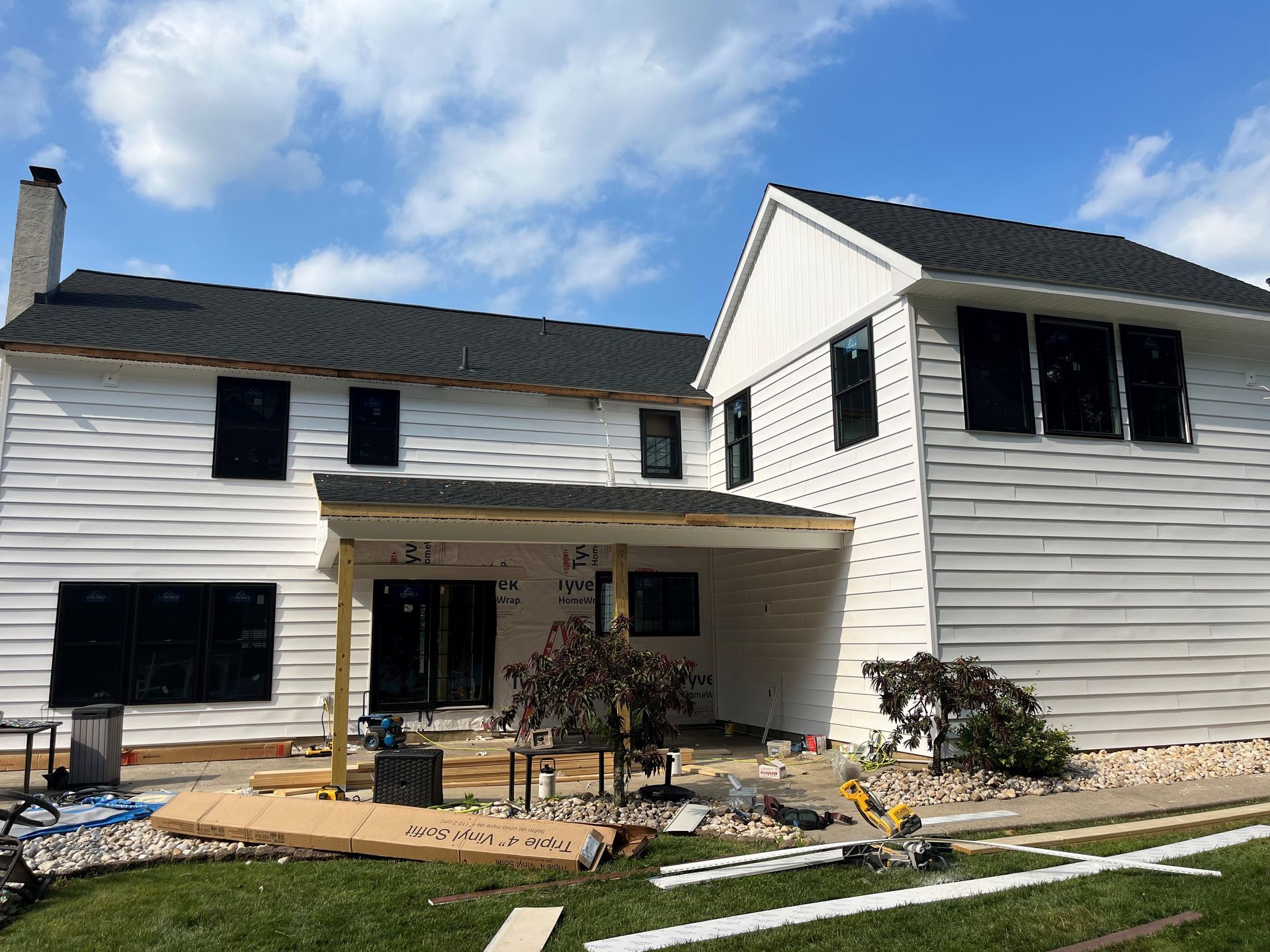 A large white house with a black roof is being remodeled.
