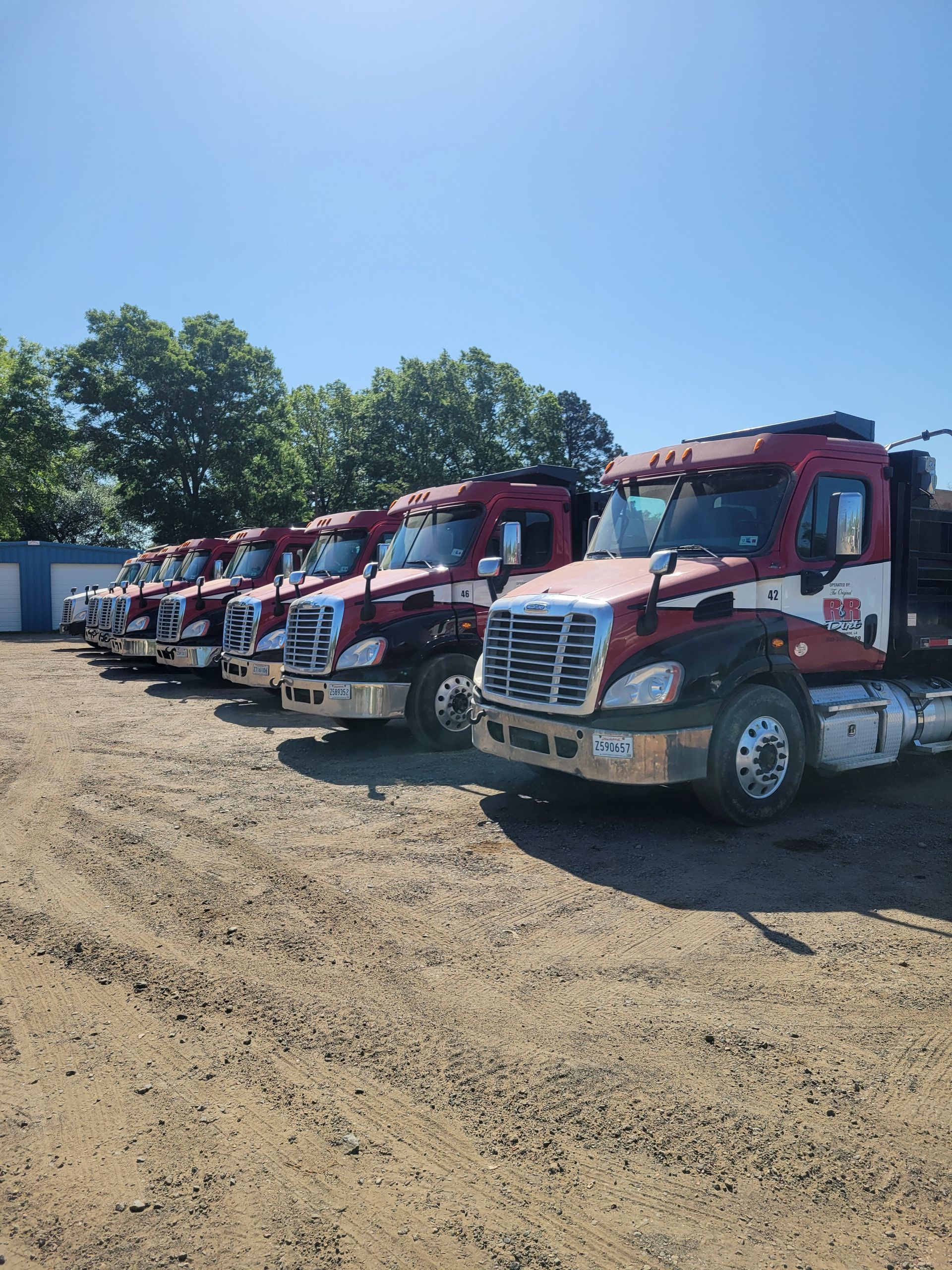 A row of red and silver semi-trucks parked.
