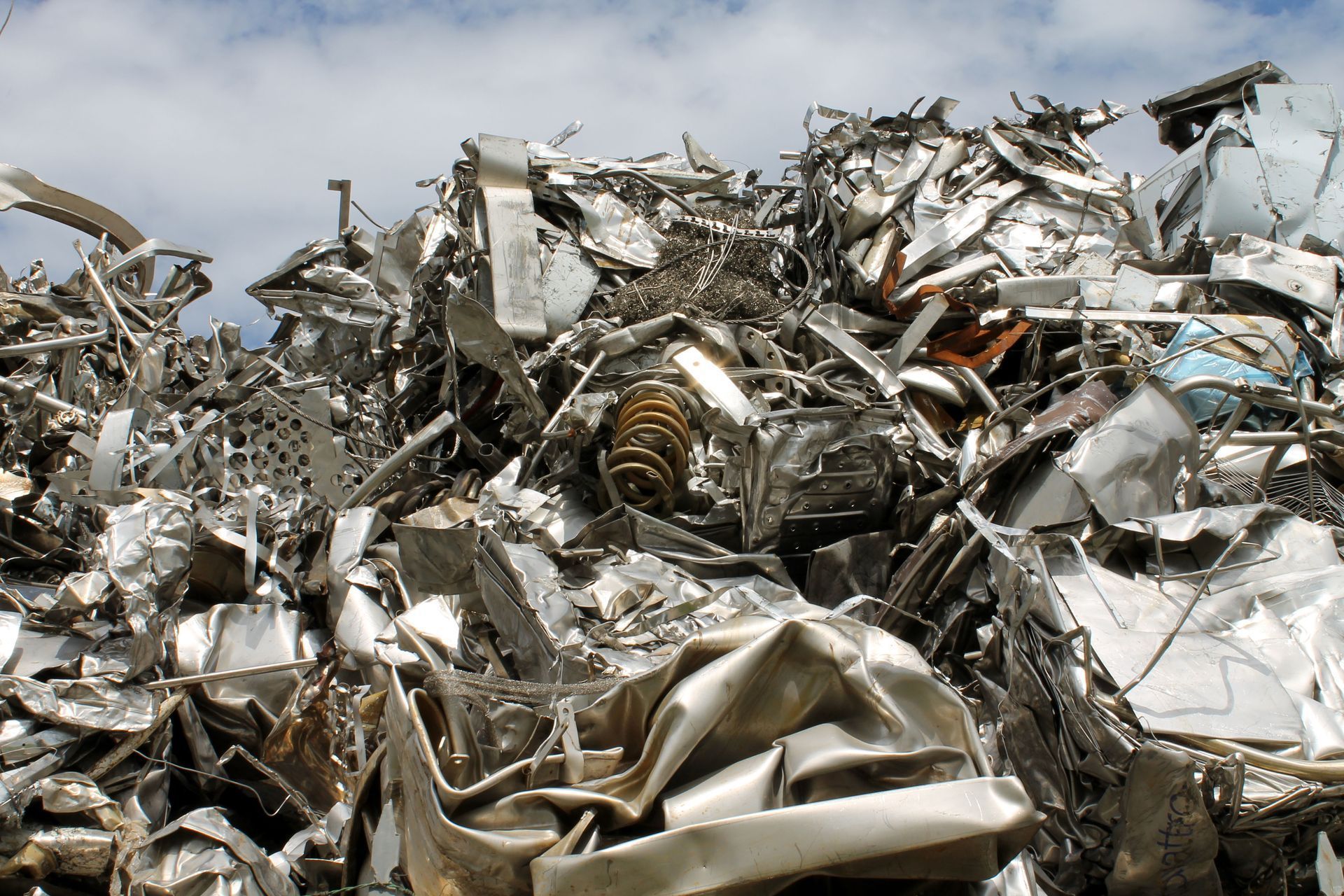 Pile of various-shaped, silvery aluminum scrap metal pieces.