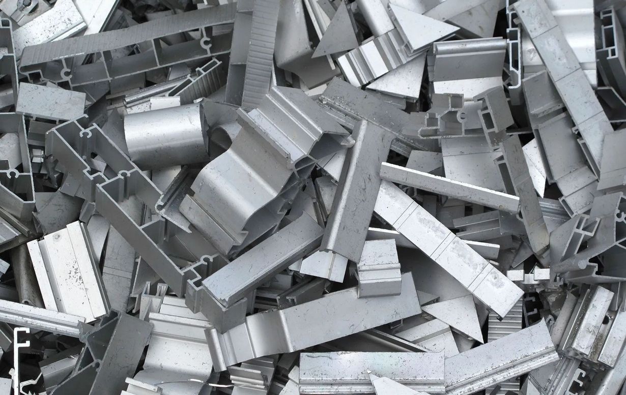 Pile of various-shaped, silvery aluminum scrap metal pieces.