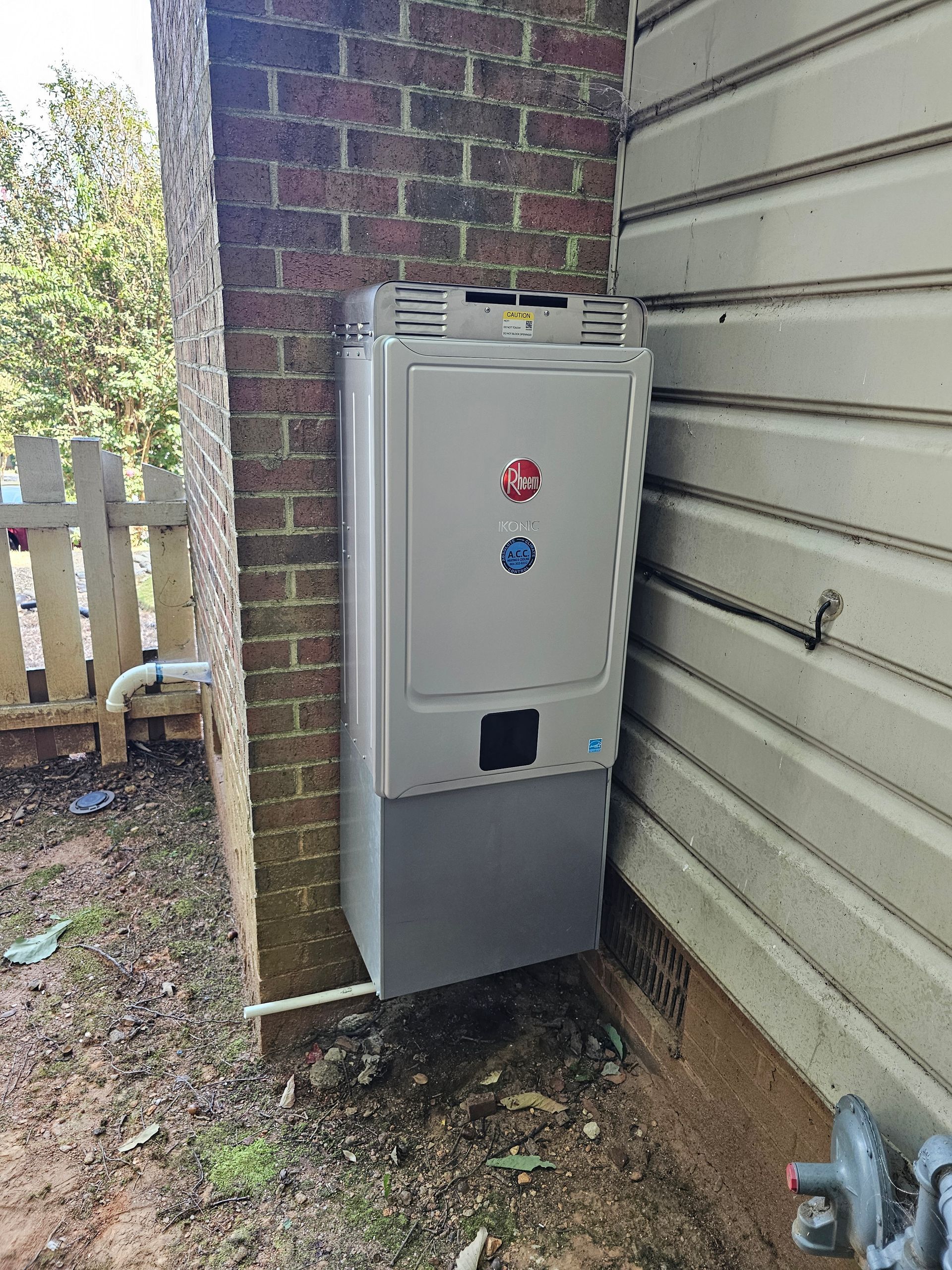 A water heater is installed on the side of a brick building