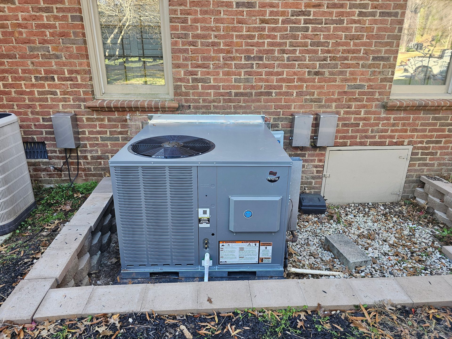 A large air conditioner is sitting on the side of a brick building