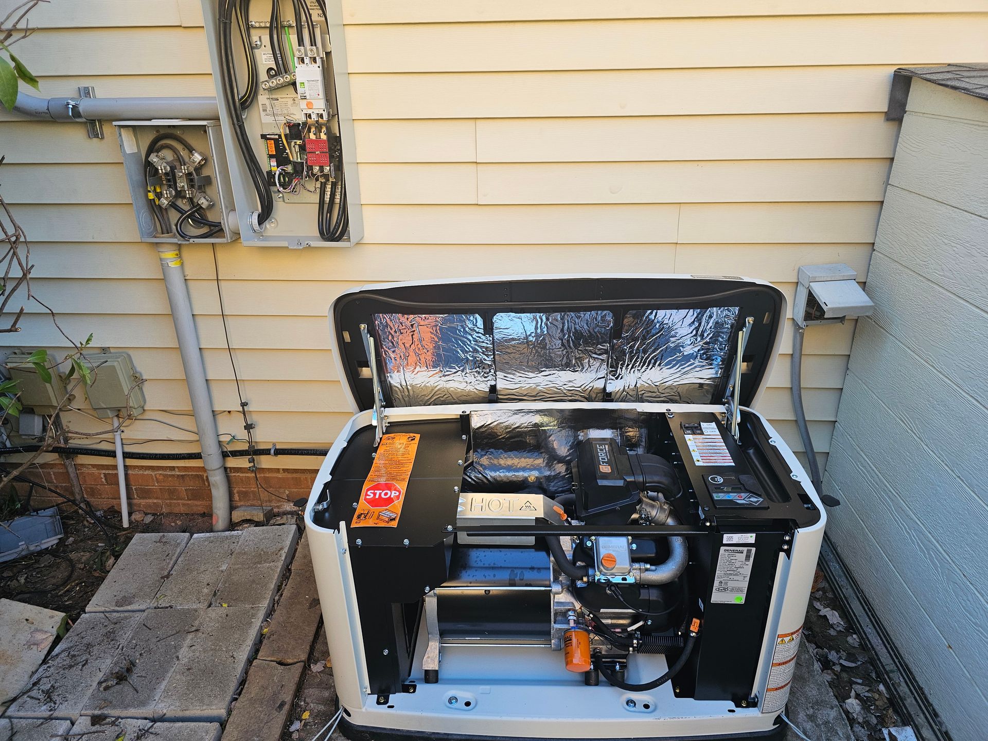 A generator is sitting outside of a house with the lid open